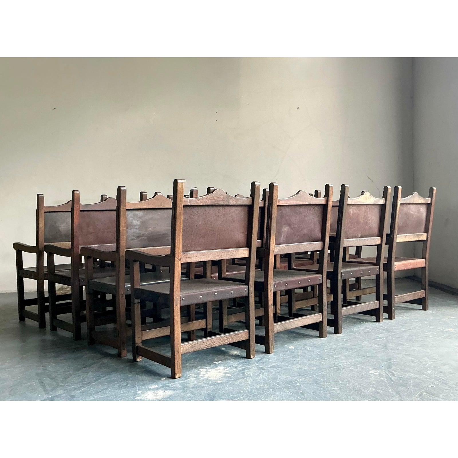 Anchor your dining space with the timeless gravitas of this magnificent set of sixteen hand-crafted Spanish Revival dining chairs. Constructed from solid wood, each chair boasts a stately silhouette with beautifully carved details and a rich, warm