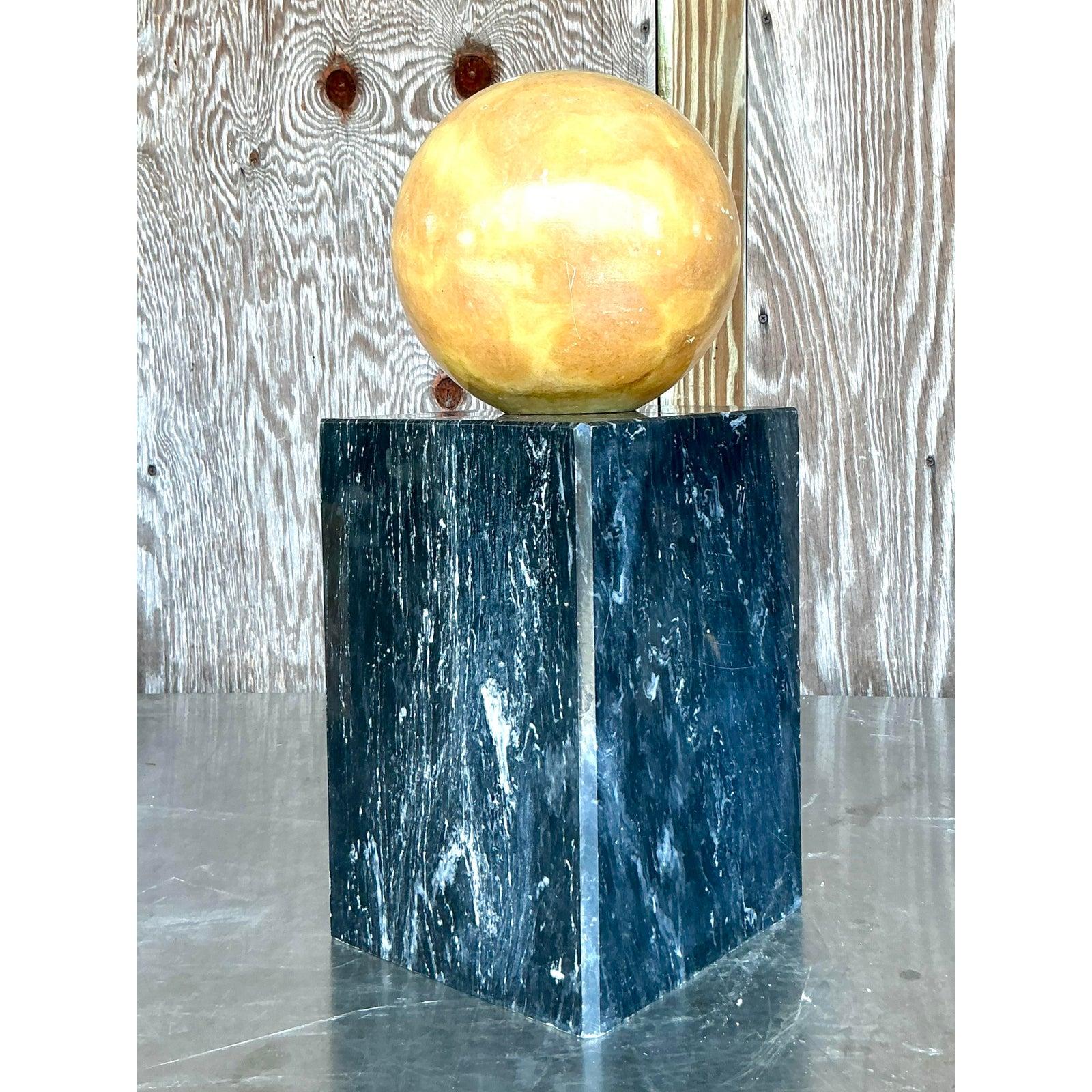 Cattura l'essenza del design postmoderno con questa straordinaria scultura geometrica vintage. Questo imponente pezzo presenta un drammatico contrasto di forme e materiali, abbinando una pesante sfera di onice di grandi dimensioni a un elegante