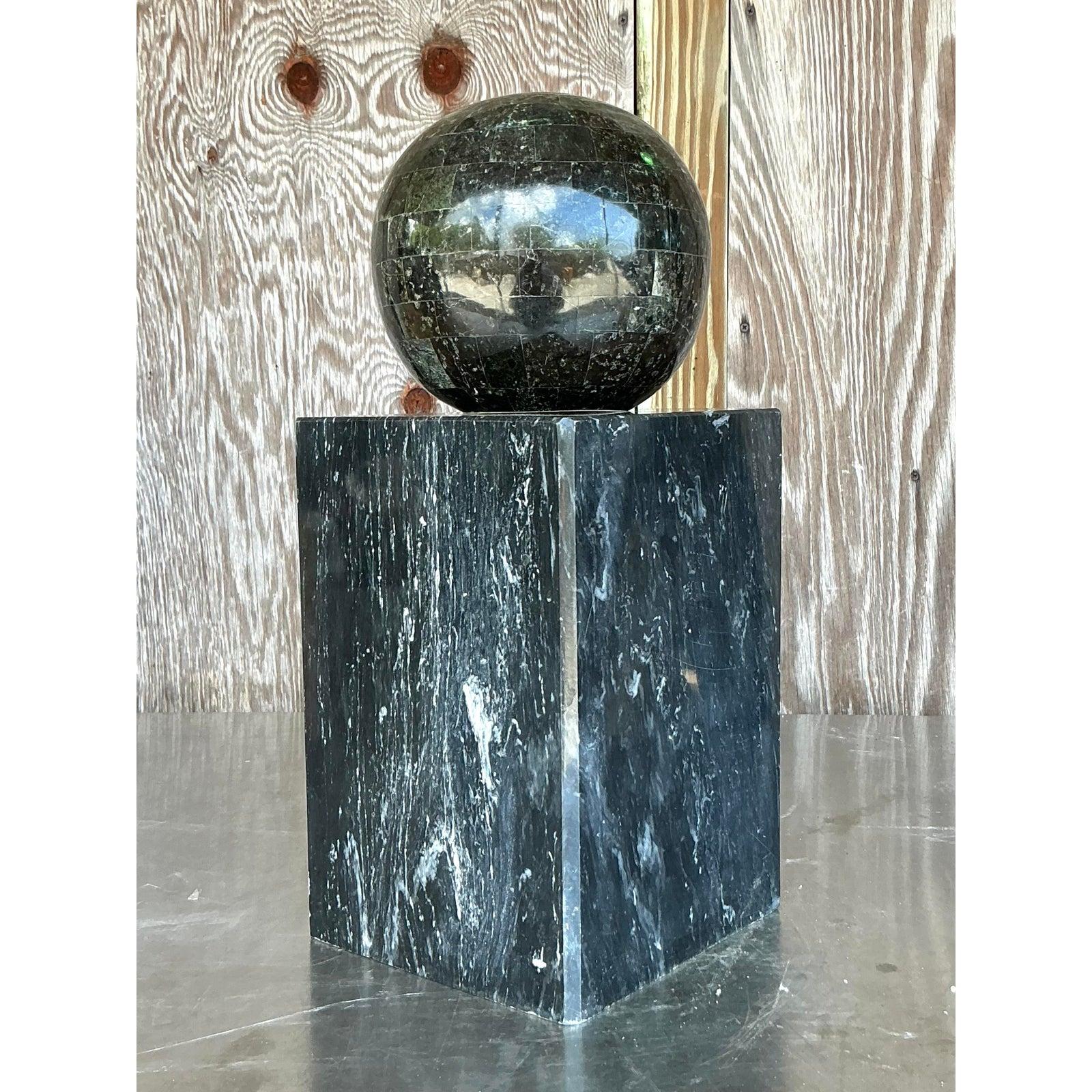 Questa scultura monumentale d'epoca, che emana un glamour grafico e audace, è uno splendido esempio di design postmoderno degli anni Ottanta. L'opera è caratterizzata da un'imponente sfera di grandi dimensioni realizzata con una pietra verde scuro o