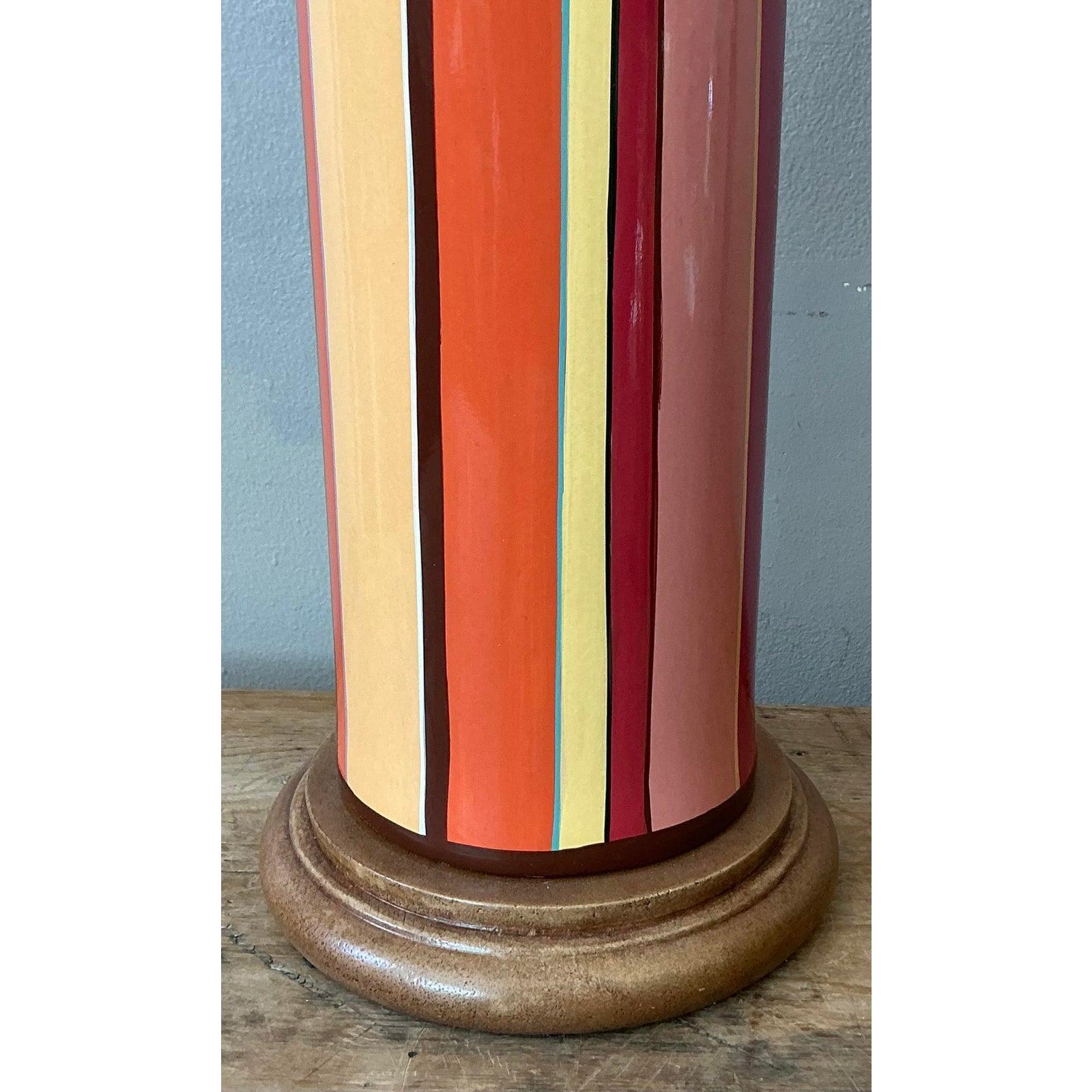 This exceptional vintage table lamp captures the vibrant, maximalist spirit of the 1970s with its sculptural, bottle-form silhouette and bold aesthetic. Handcrafted from glossy glazed ceramic, the body features a striking pattern of vertical stripes