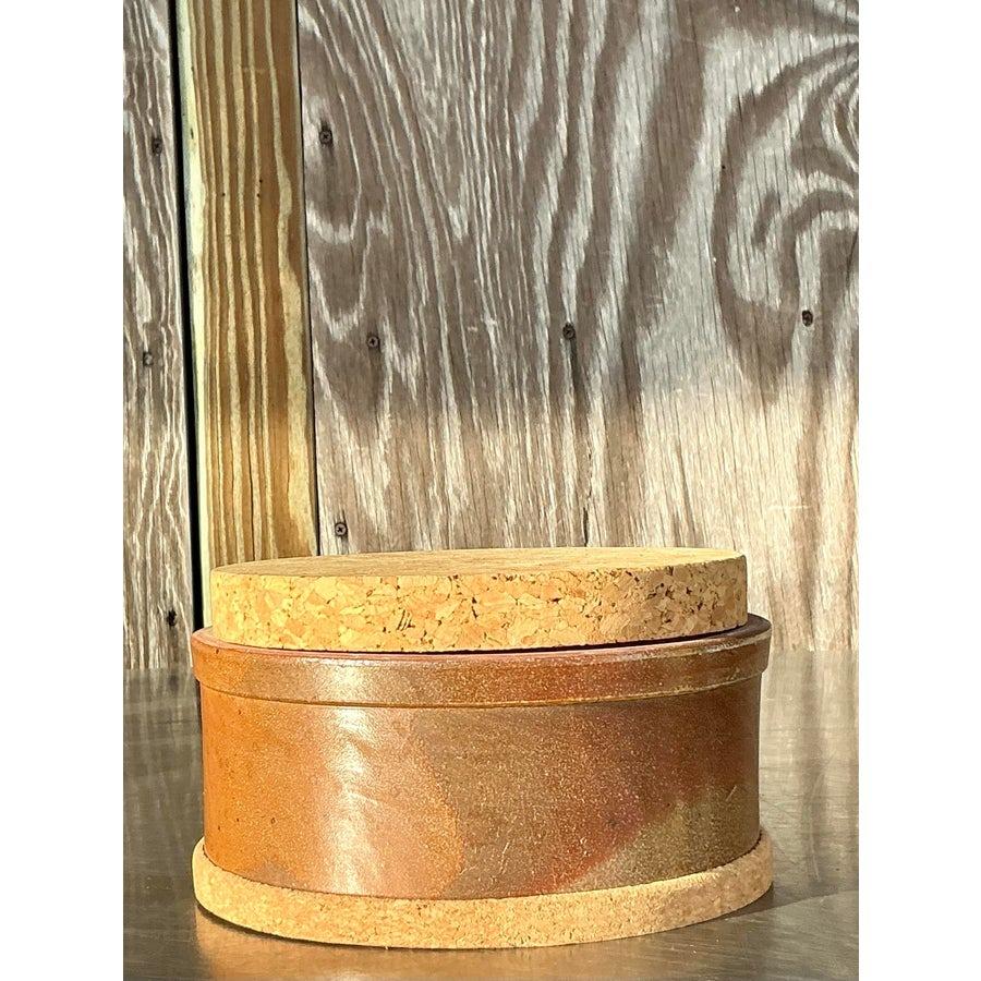 This beautiful vintage studio pottery lidded bowl brings a touch of rustic charm and functionality to your home decor. The bowl features a rich earthy glaze in warm brown tones, complemented by a perfectly fitted cork lid. Its handcrafted design