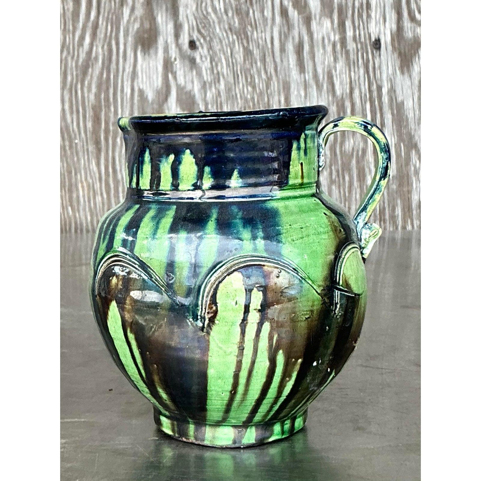 Add vibrant energy and earthy character to your home with this vintage studio pottery pitcher, a true celebration of artisan craftsmanship. Hand-thrown and finished in a stunning drip glaze, it features rich green and indigo tones with abstract