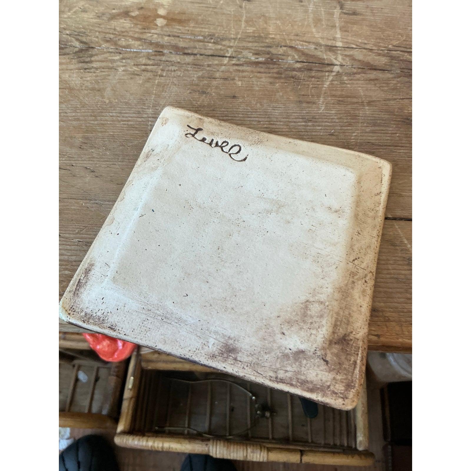 This unique studio pottery tile or small plate is a fascinating piece of handcrafted ceramics, utilizing texture and glazing to create a dynamic optical effect. Hand-formed with a slight irregularity, the square piece features a deeply impressed