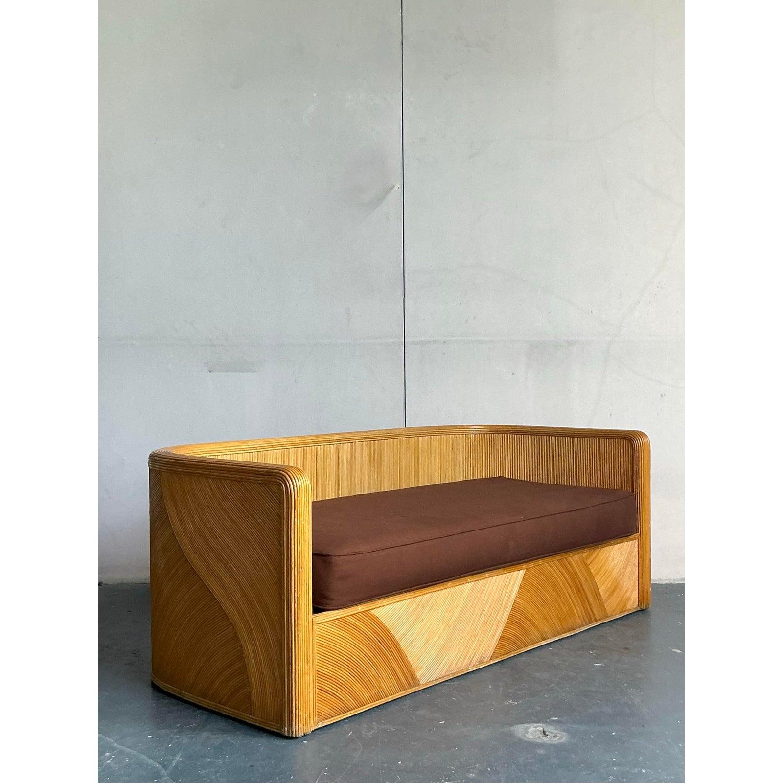 Verankern Sie Ihren Wohnbereich mit dem unbestreitbaren Glamour dieses Vintage-Schilfsofas. Dieses Meisterwerk des organischen Designs der 1970er Jahre zeichnet sich durch eine dramatische Wasserfall-Silhouette aus, bei der die Arme und der Rücken