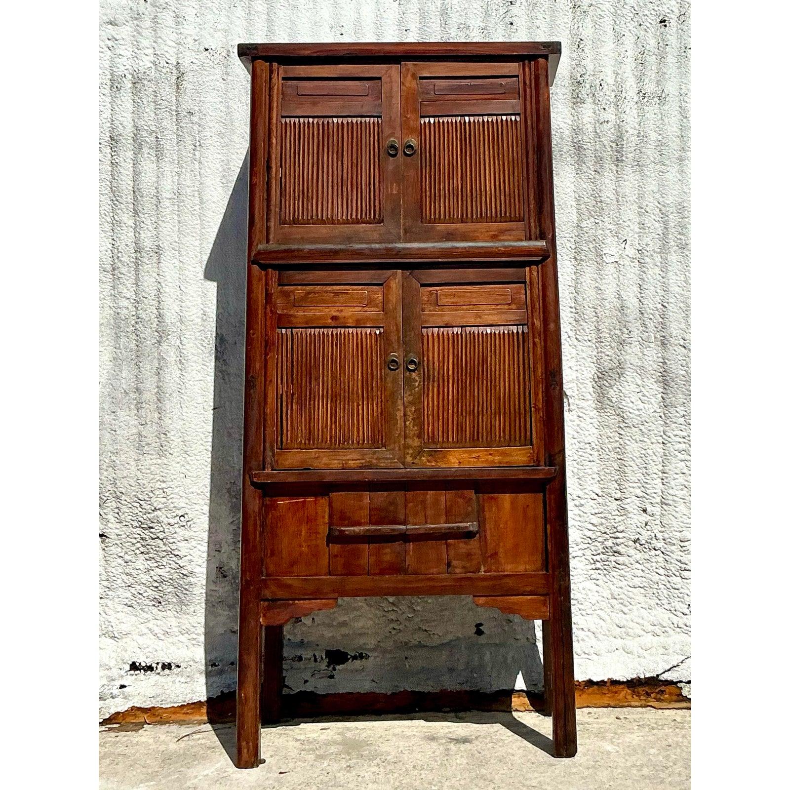 Elevate your interior with this striking vintage Boho teak tall cabinet, a beautifully handcrafted piece that blends rustic charm with timeless elegance. Featuring reeded wood panel doors and warm, aged teak, this multi-compartment cabinet showcases