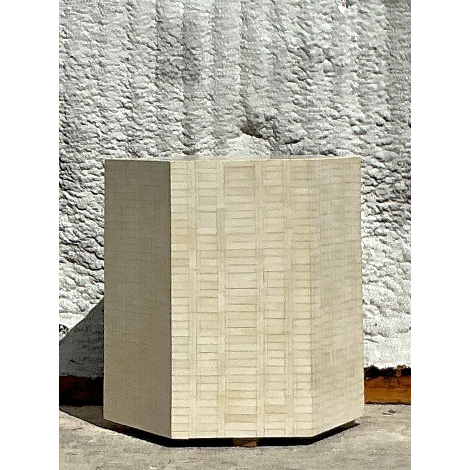 Add an element of exotic refinement to your space with this vintage tessellated bone side table. Handcrafted in a striking hexagonal silhouette, the table features a mesmerizing mosaic of bone tiles in soft ivory hues, arranged in a rhythmic pattern