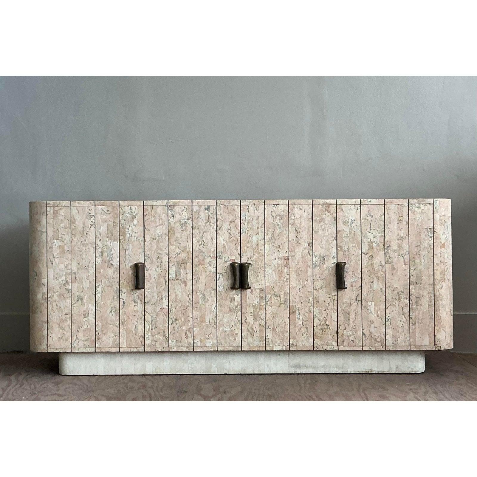 Capture the opulent spirit of 1980s design with this breathtaking tessellated travertine credenza. Meticulously handcrafted, this piece features panels of warm, rose-hued travertine arranged in a striking vertical pattern, creating a rich and