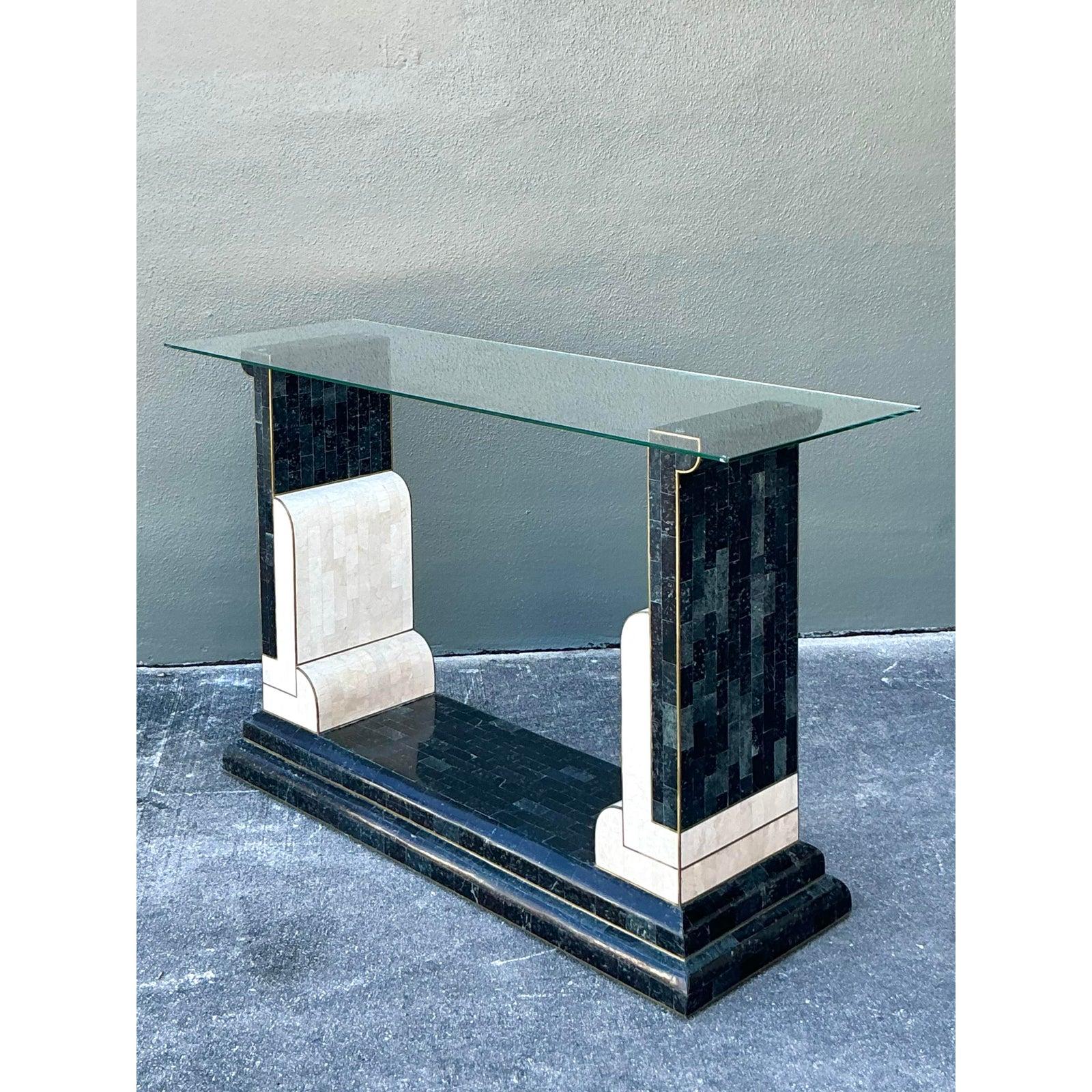 This striking console table is a magnificent expression of Art Deco Revival, utilizing bold geometry and dramatic material contrast characteristic of high-style 1980s design. The base features a tiered black plinth supporting two vertical end