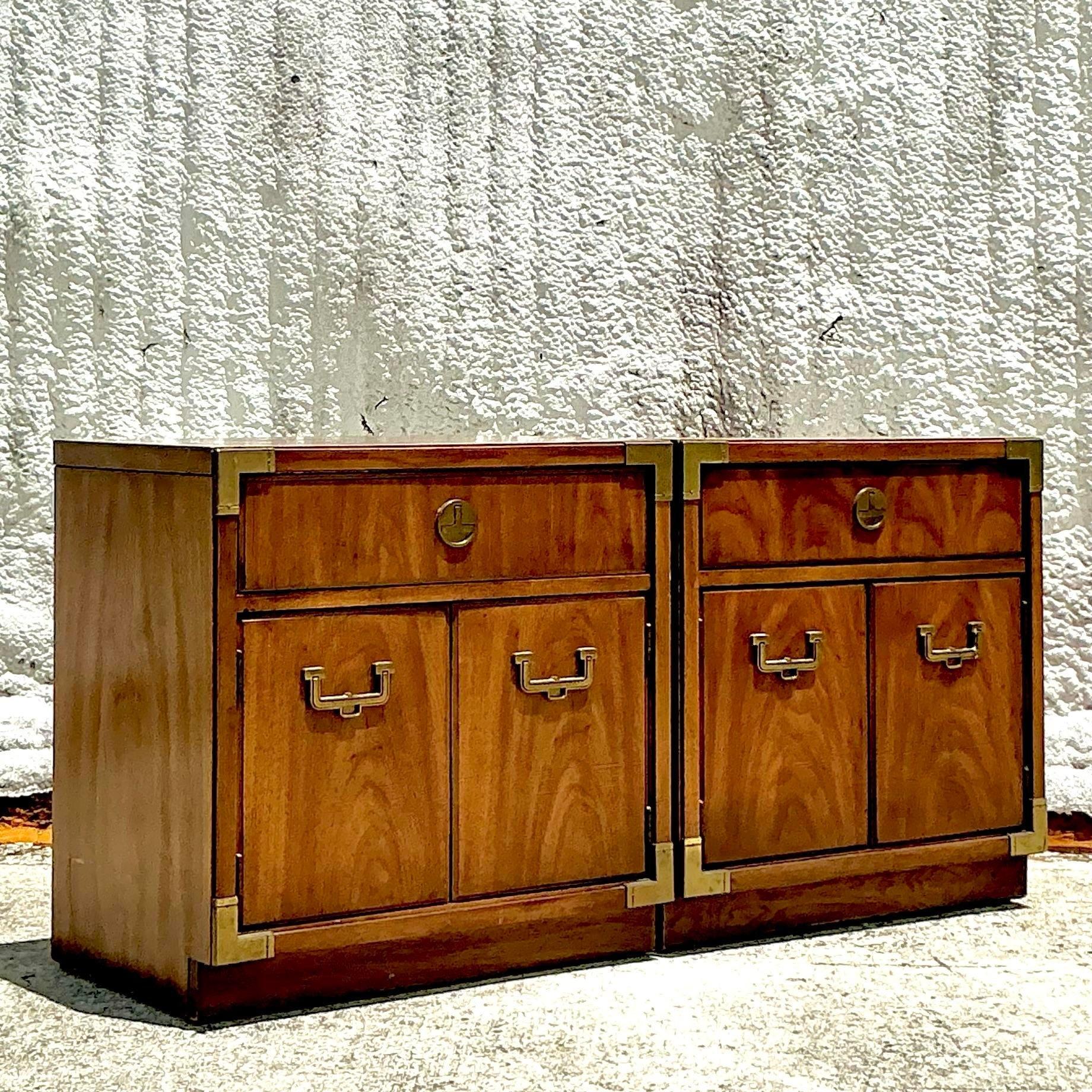 Elevate your bedroom decor with this pair of Vintage Boho Thomasville Campaign Nightstands. Perfect for American-style interiors, these nightstands feature the distinctive Campaign-style brass hardware and clean lines, combined with a Boho twist.