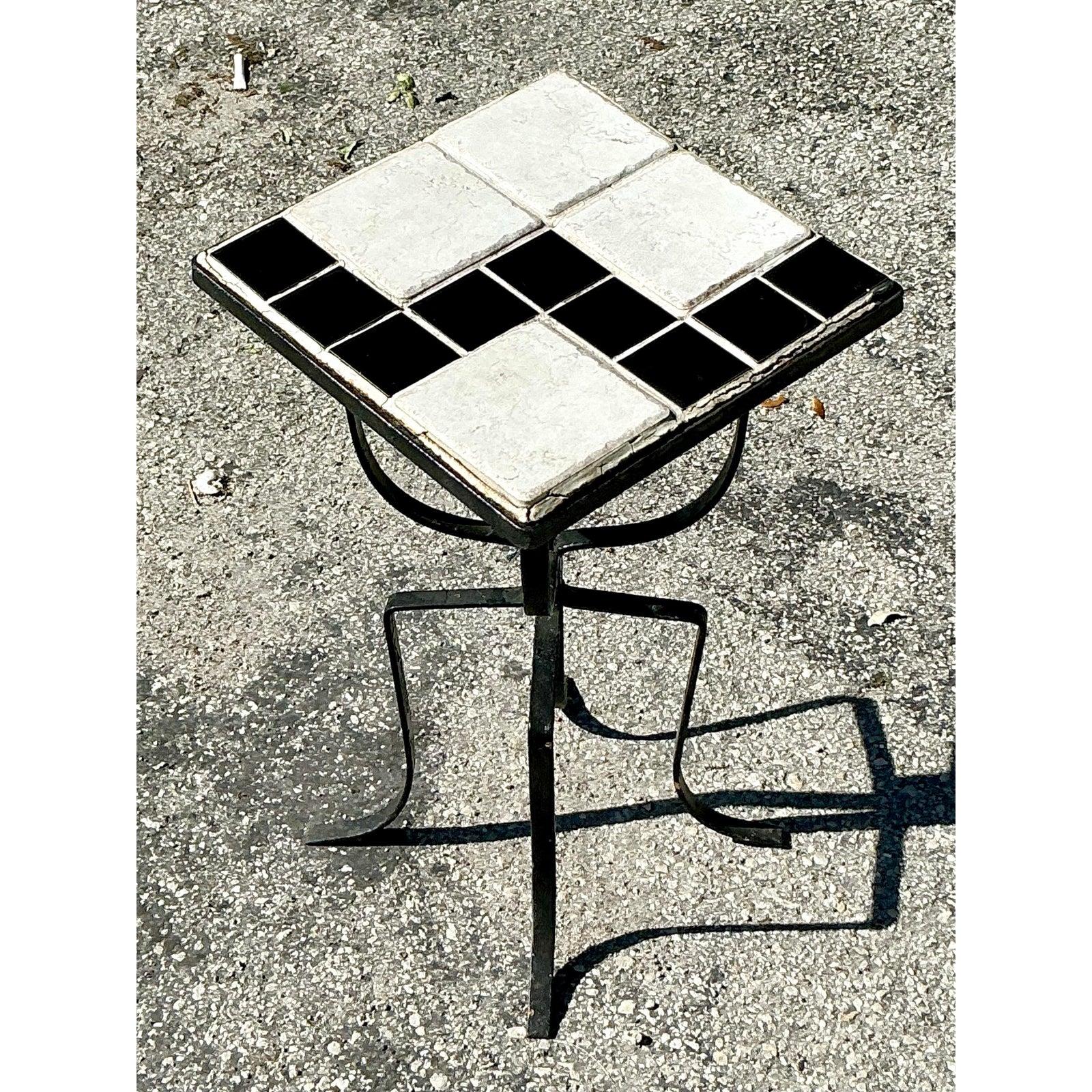 Cette table à boissons boho vintage apporte une touche de charme artistique avec son plateau en carrelage noir et blanc saisissant, enchâssé dans une base robuste en fer forgé. Le motif contrasté des carreaux ajoute un intérêt visuel, ce qui en fait
