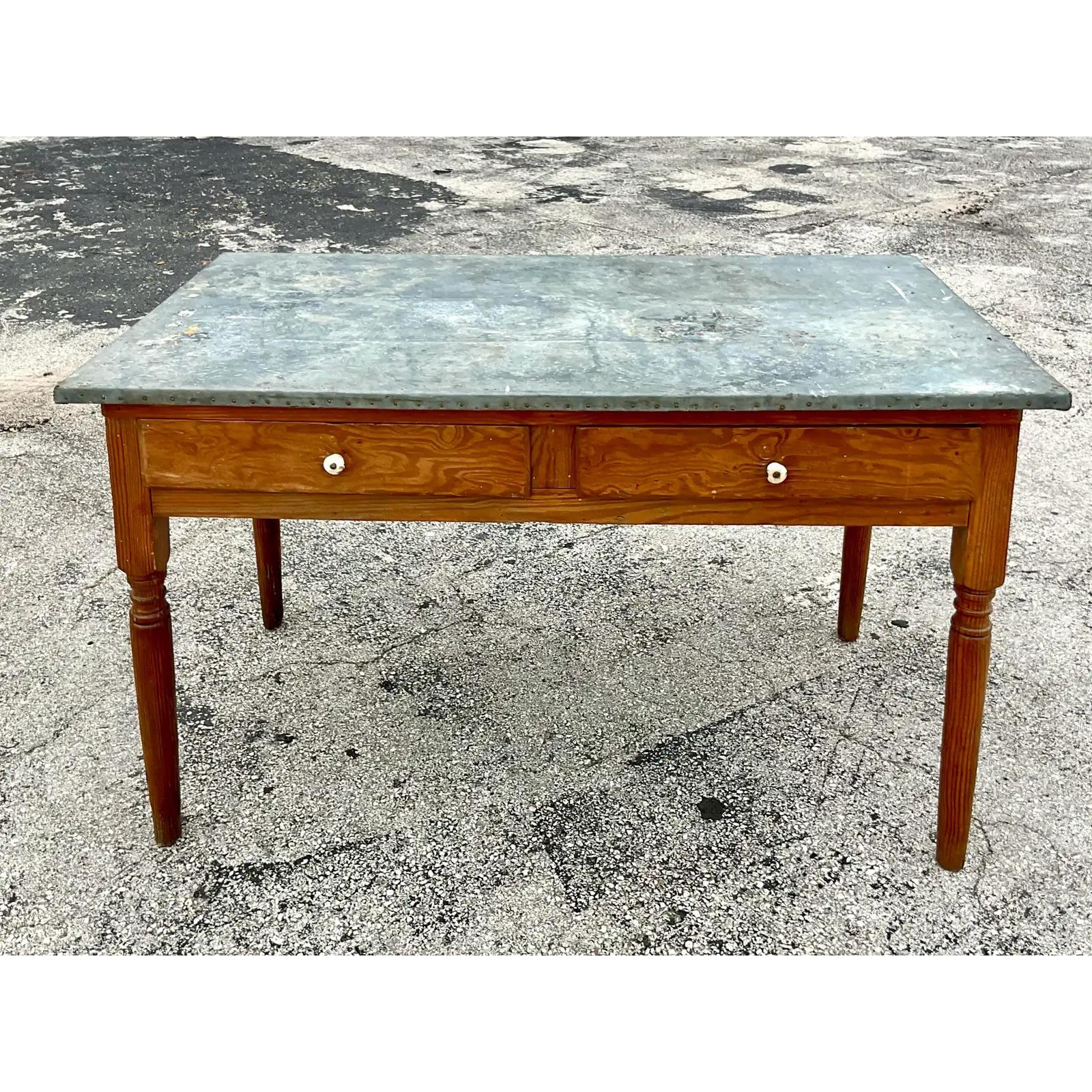 A striking vintage Boho dining table. Chic tin wrapped top with hand hammered nails along the edge. The perfect amount of all over distressed finish for that farm house look. Acquired from a Palm Beach estate.
