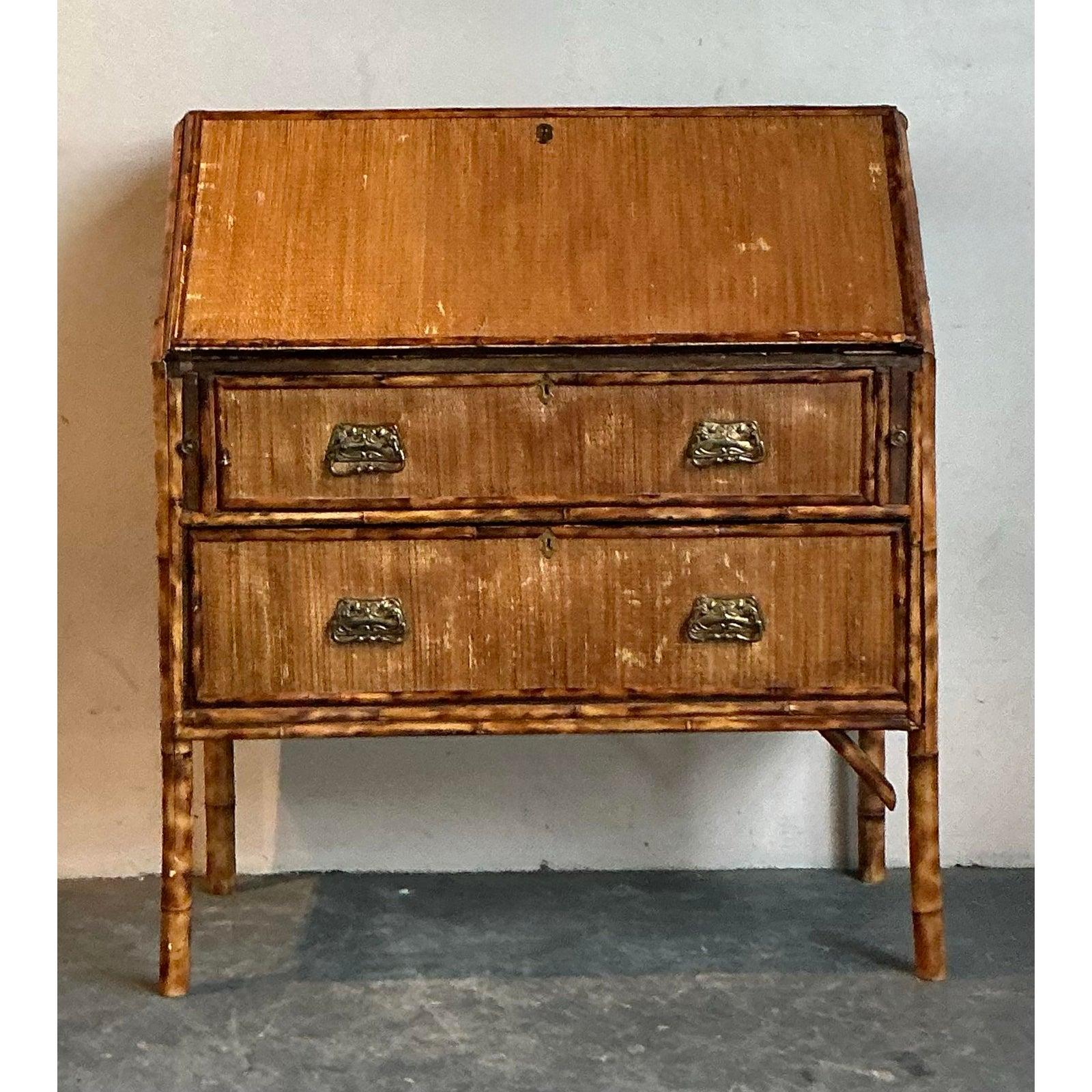 This charming vintage secretary desk captures the free-spirited essence of Boho Chic with its distinctive tortoise bamboo and woven cane construction. A testament to artisanal craftsmanship, the desk features a rich, variegated finish that