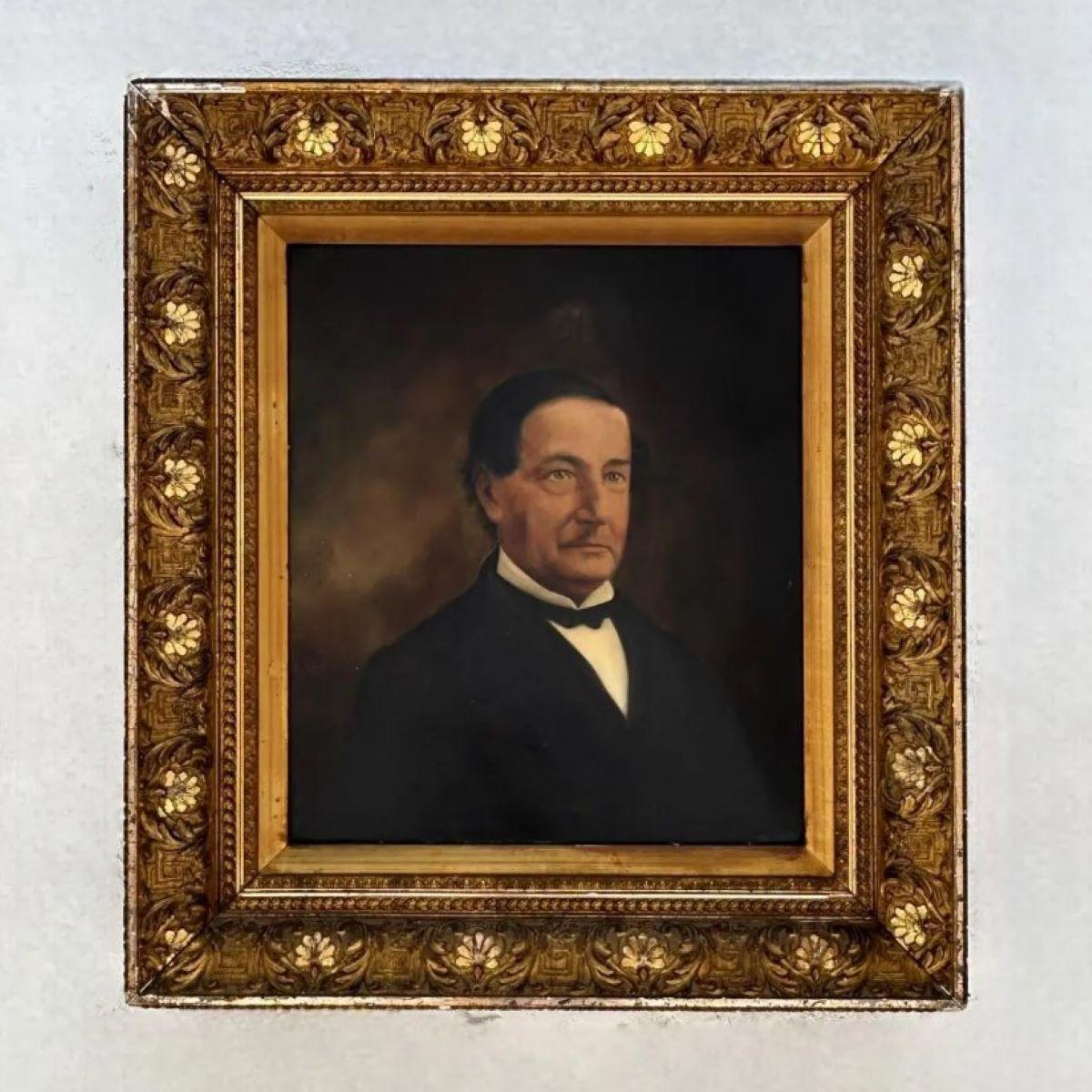 Dieses stattliche antike Ölporträt zeigt einen würdevollen Herrn vor einem schattigen braunen Hintergrund, der zeitlose Eleganz und Förmlichkeit ausstrahlt. Gekleidet in einen klassischen schwarzen Anzug mit weißem Hemd und schwarzer Fliege, blickt