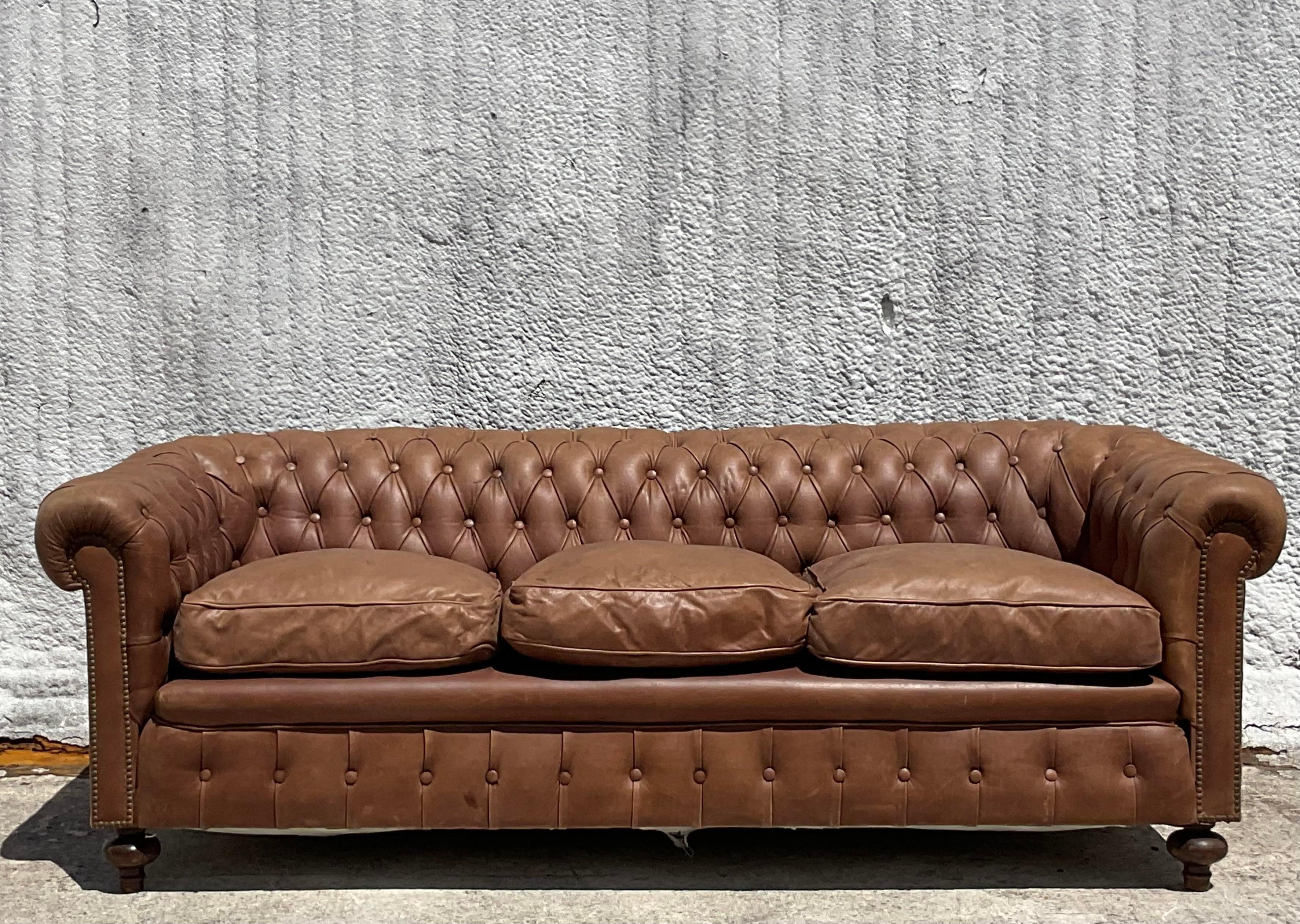 Elevate your living space with this Vintage Boho Tufted Leather Chesterfield Sofa, blending classic American craftsmanship with Bohemian allure. Adorned with tufted detailing and supple leather, it embodies the timeless sophistication of a