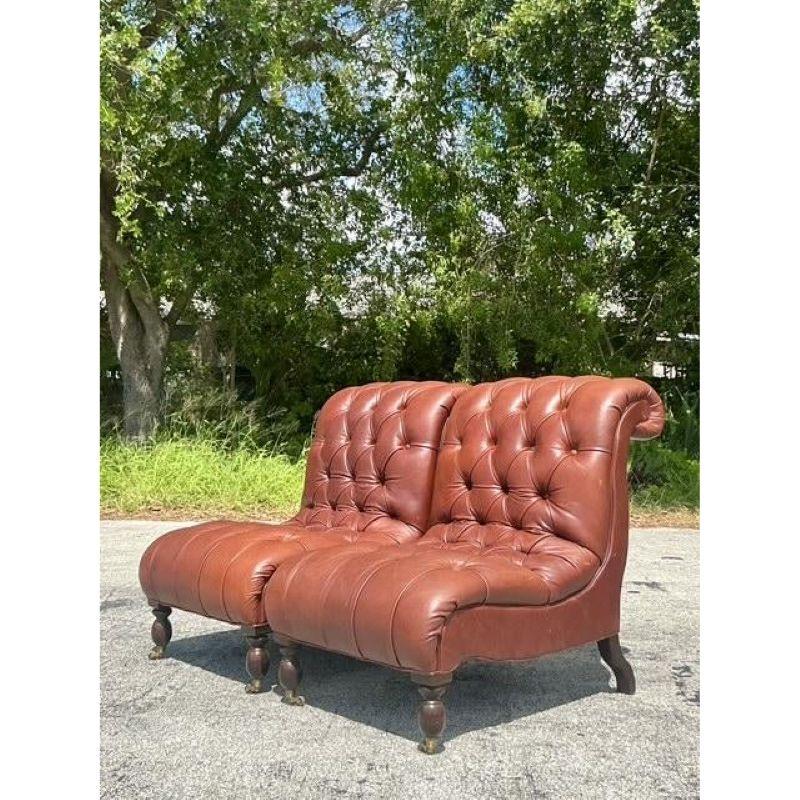 Exuding the timeless, comfortable elegance of a classic English library, this exceptional pair of slipper chairs is designed in the celebrated manner of George Smith. Each chair is masterfully upholstered in a rich, supple brown leather, featuring