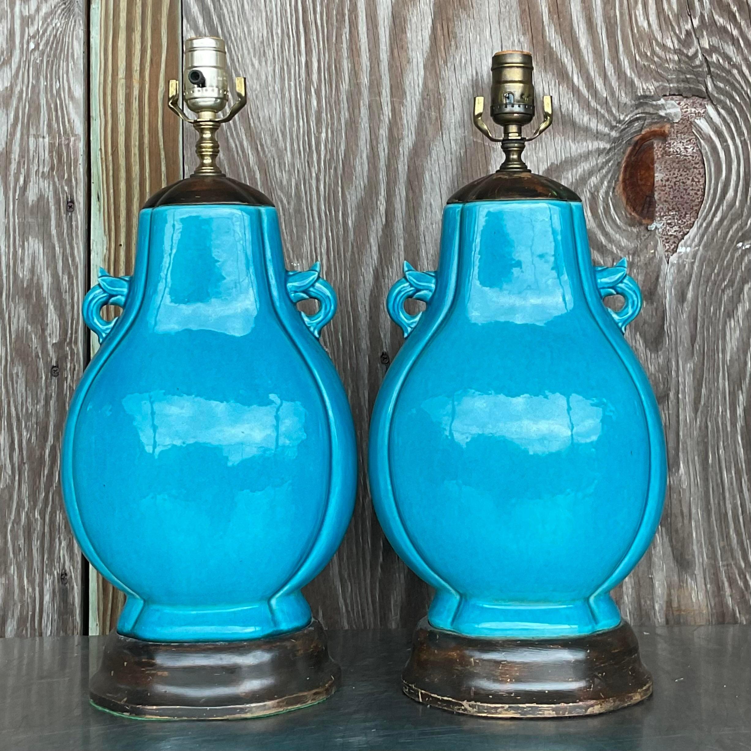 Une paire spectaculaire de lampes de table Boho vintage. Un magnifique bleu turquoise vif dans une finition en céramique émaillée. Ils reposent sur des socles en bois ébonisé. Acquis d'une succession de Palm Beach