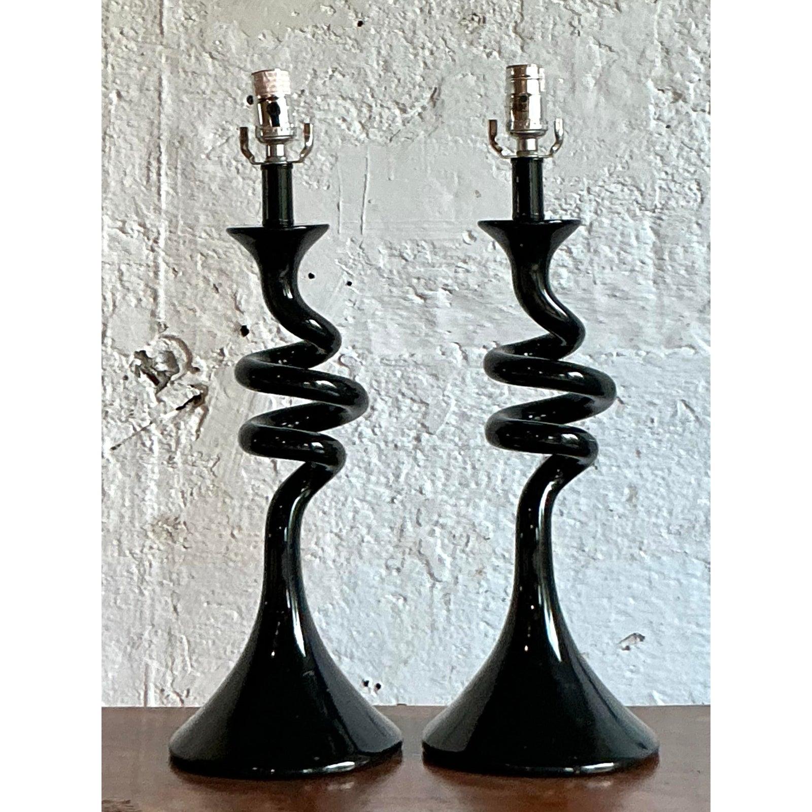 Illuminate your interior with the dramatic flair of this stunning pair of vintage black glass lamps. Each lamp features a masterfully crafted, spiraling body that evokes the sculptural elegance of Italian Murano glass, rising from a classic