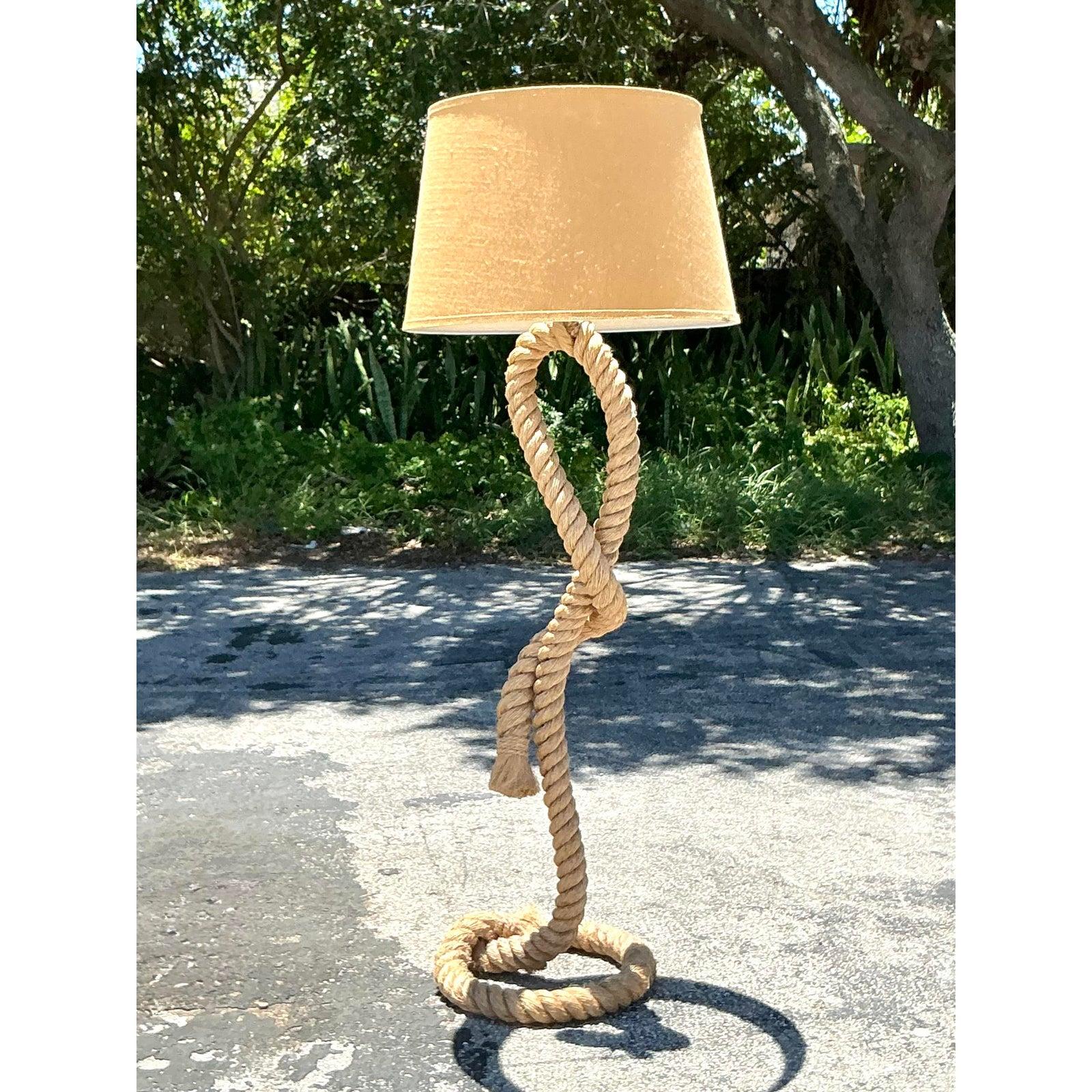 Illuminate your space with the captivating texture and sculptural artistry of this vintage twisted rope floor lamp. Masterfully crafted from thick, natural rope, the lamp's body is coaxed into a dynamic, serpentine form, anchored by an expressive