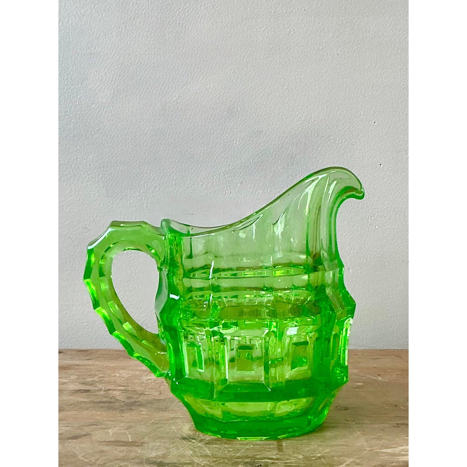 Discover the captivating charm of this vintage Boho Chic Vaseline Glass Pitcher, a radiant piece that instantly brightens any collection. Crafted from the distinctive uranium-infused glass, this pitcher glows vibrantly under UV light, showcasing its