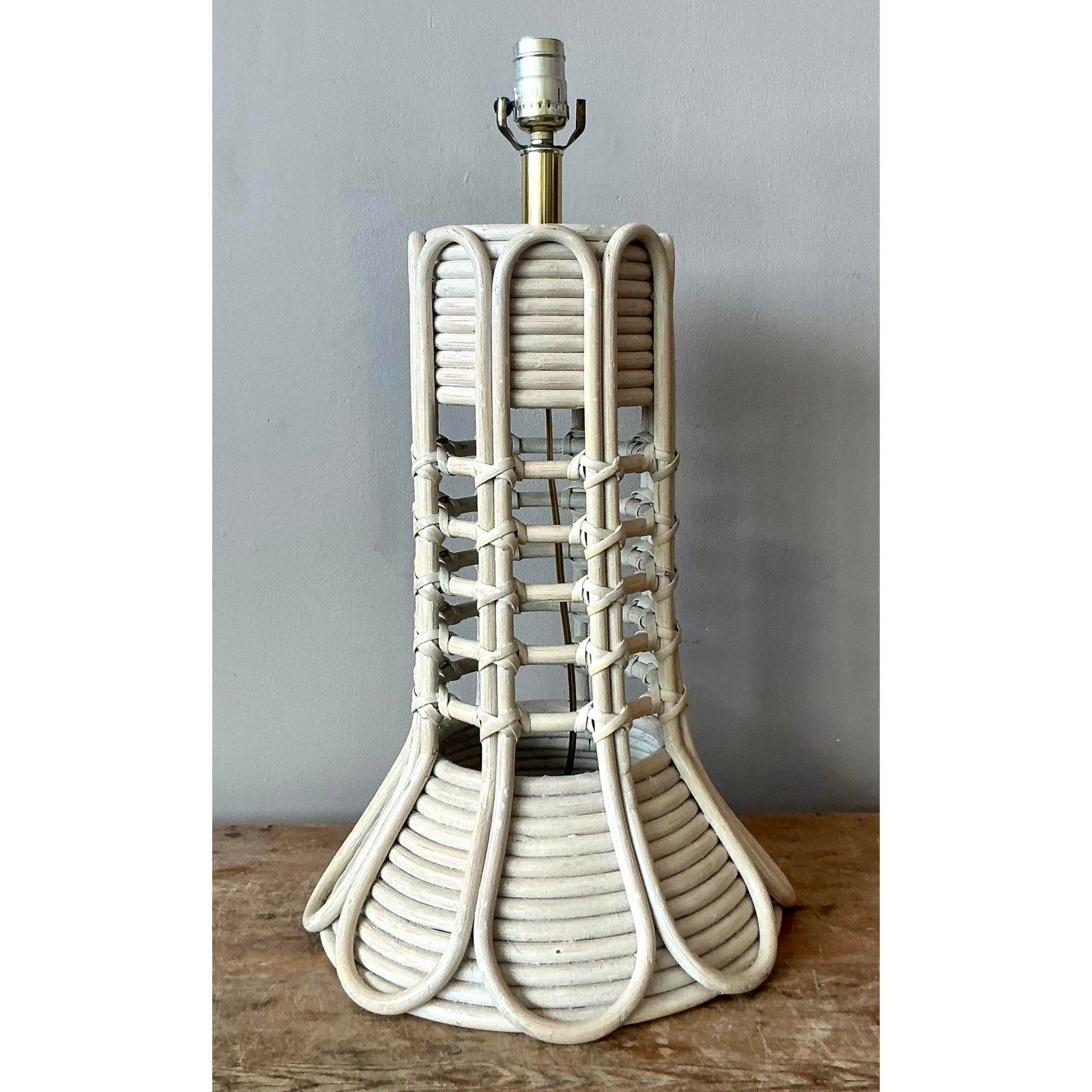 Illuminate your interior with the sculptural elegance of this vintage pencil reed and rattan table lamp. The design features a striking architectural silhouette, characterized by a cylindrical top and a flared base, connected by an airy, open-work