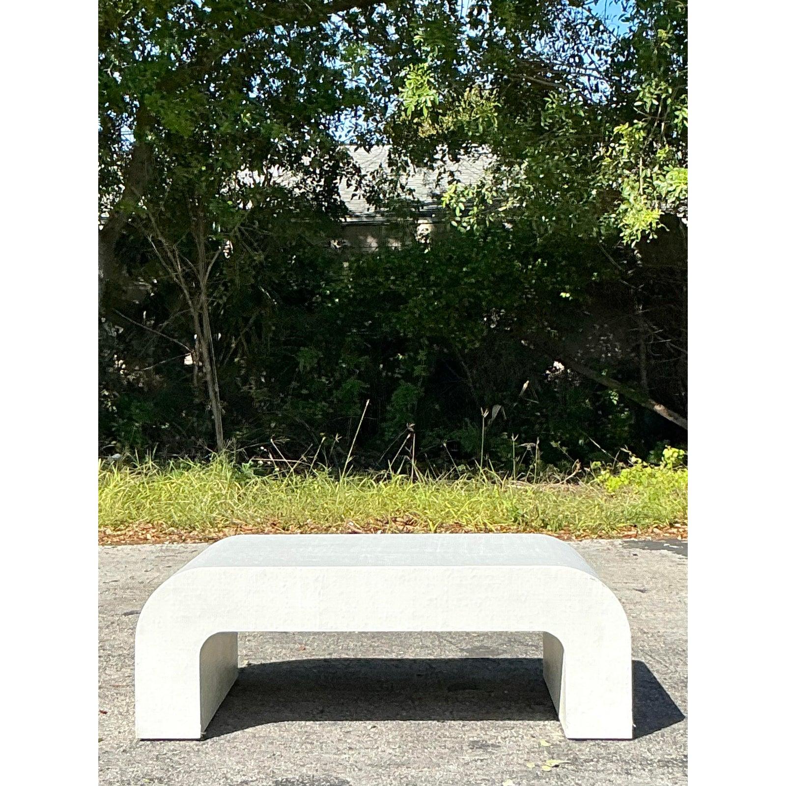 Cette étonnante table basse vintage en cascade présente une silhouette élégante et incurvée enveloppée dans une luxueuse toile d'herbe, offrant un mélange intemporel de texture organique et d'élégance moderne. Le design en cascade rehausse son