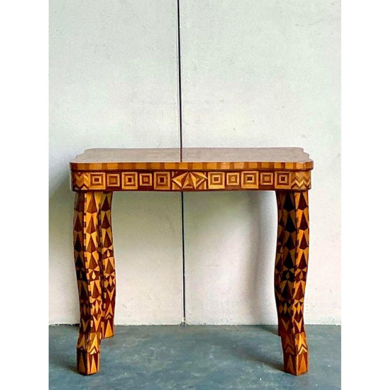 This exquisite vintage side table, dating from the early 20th century, showcases a captivating bohemian charm with its intricate marquetry work. Crafted from various woods, the geometric patterns adorning every surface—from the subtly curved legs to