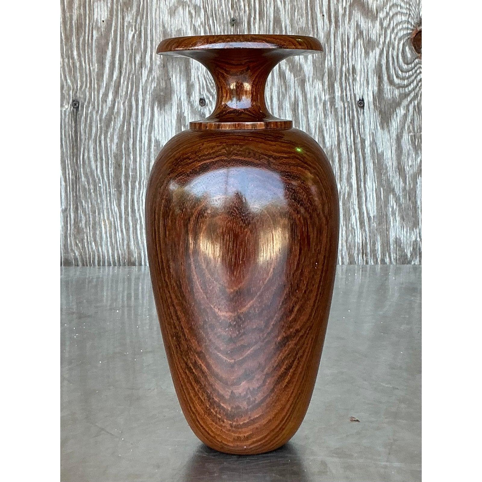 Add a touch of warm, organic beauty to your home with this vintage vase, skillfully crafted from a solid piece of wood through the art of wood turning. This elegant piece features a smooth, contoured silhouette that beautifully showcases the natural