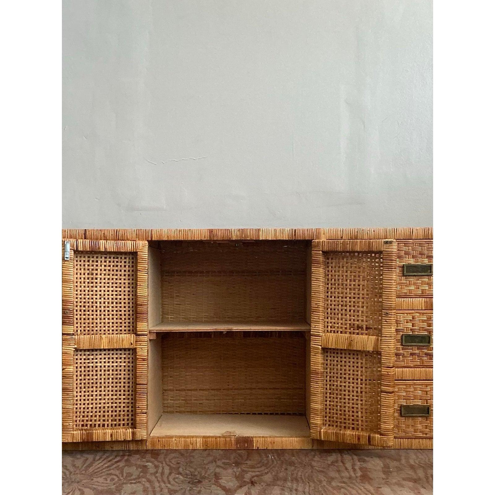 Introduce a wave of organic warmth and texture into your space with this stunning vintage woven rattan credenza. A masterpiece of craftsmanship, this piece showcases an intricately detailed basketweave pattern across its facade and sides, creating a