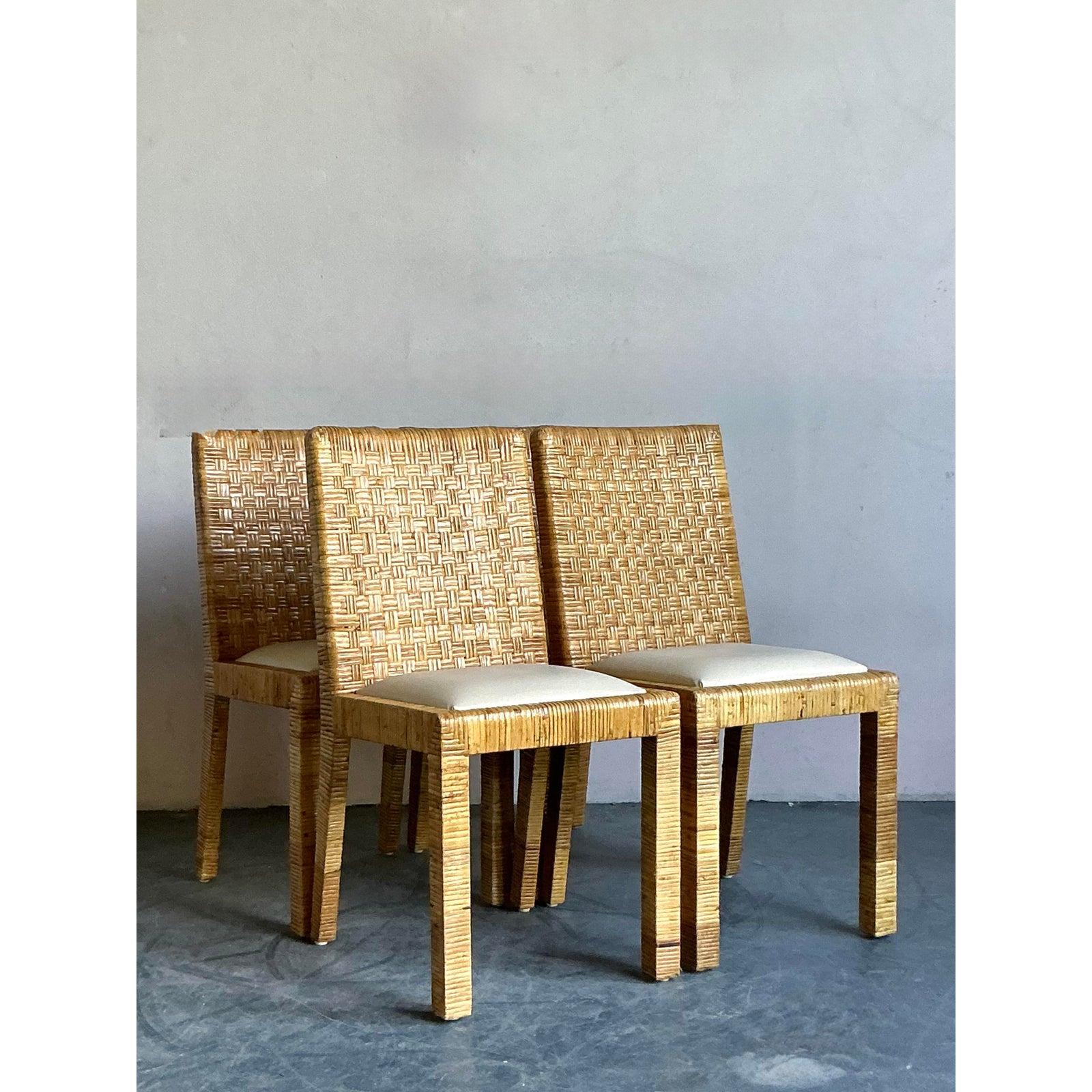 Infuse your dining space with a dose of coastal elegance with this exceptional set of four vintage woven rattan chairs. Expertly handcrafted, each chair showcases a stunning basketweave texture that fully envelops its clean, geometric frame, a