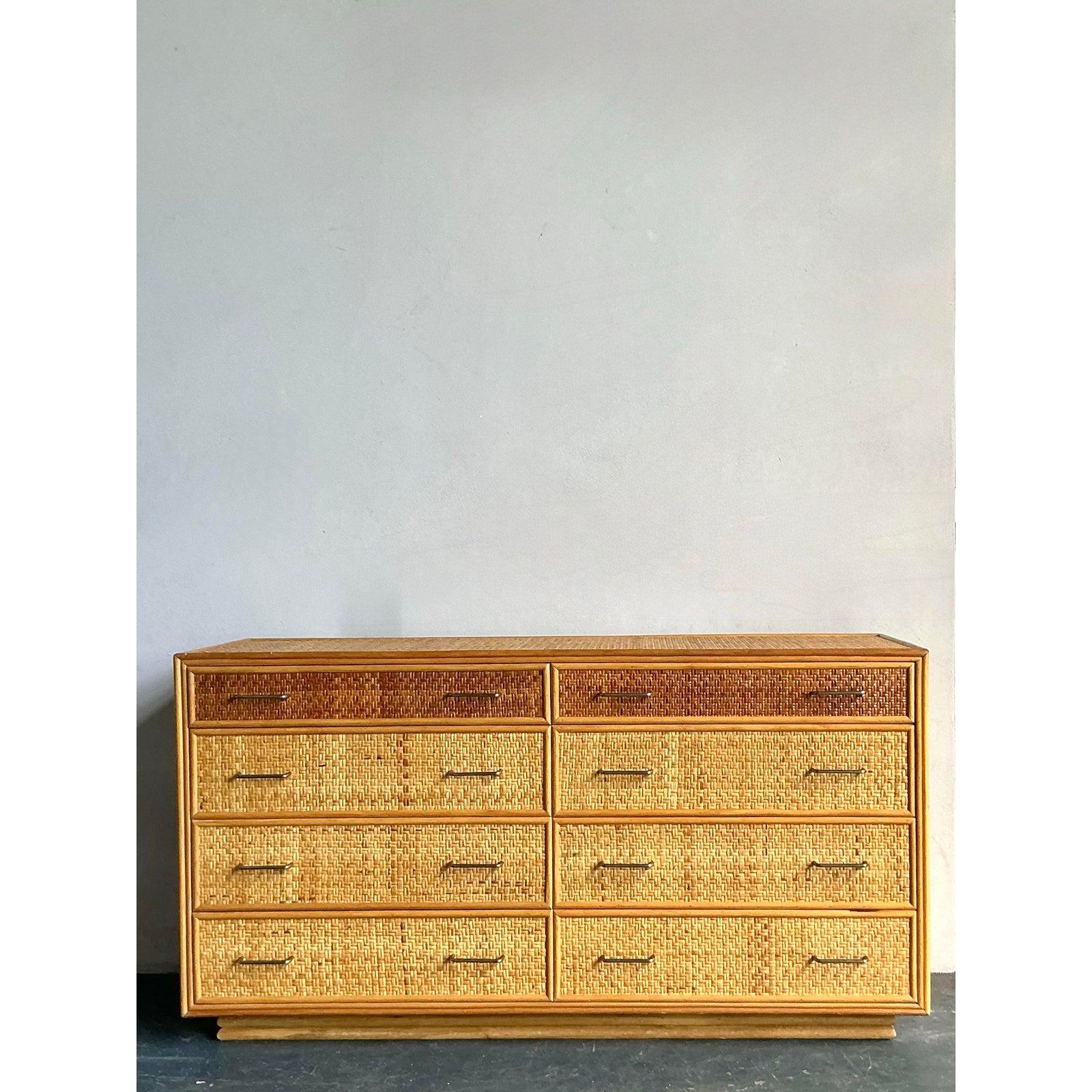 Abbraccia la raffinatezza rilassata di questa cassettiera vintage in rattan intrecciato Boho, un pezzo straordinario che fonde perfettamente texture naturali e influenze Mid-Century Modern. Realizzato con intricati dettagli in rattan intrecciato,