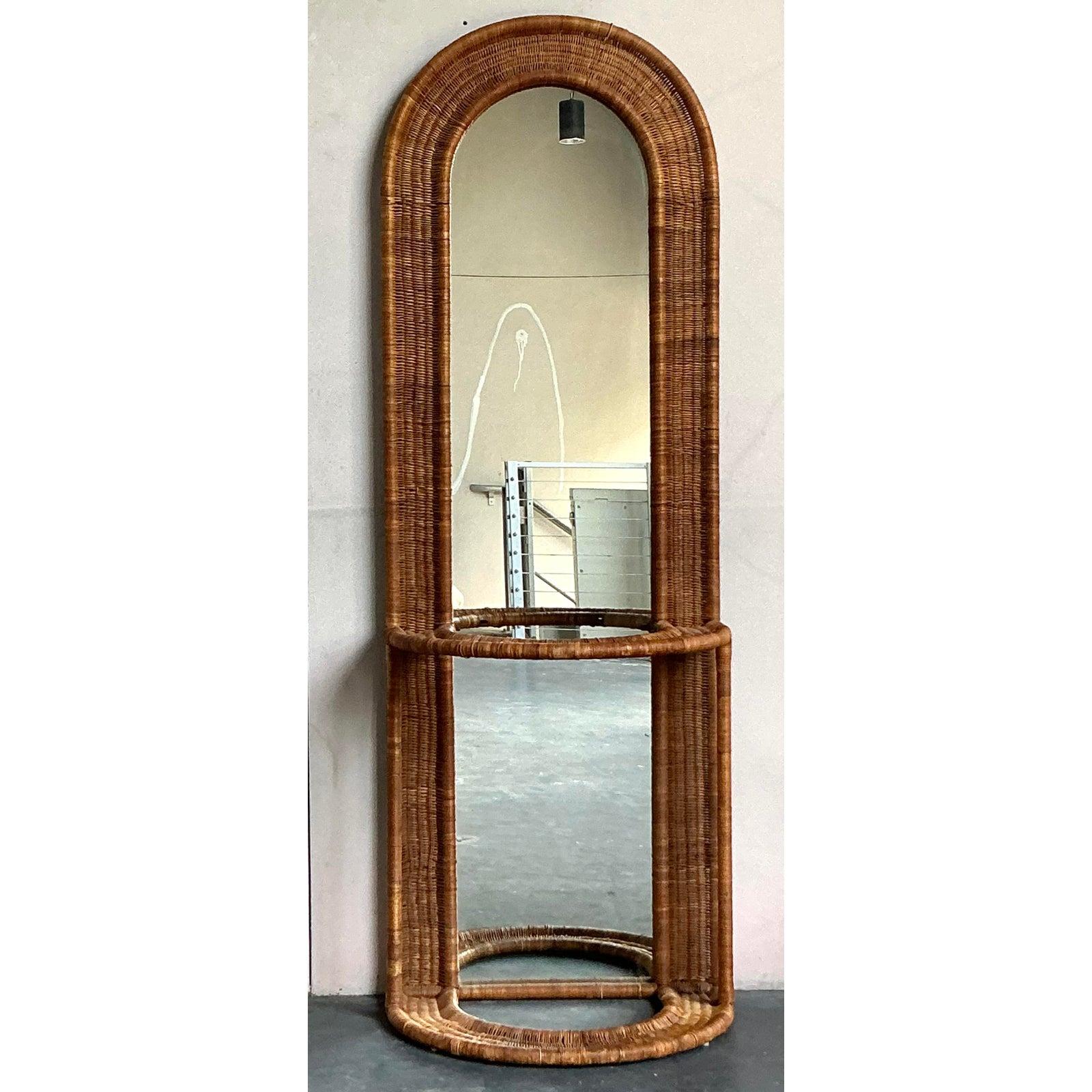 Dieser außergewöhnliche Vintage-Dielenbaum verleiht Ihrem Raum den mühelosen Stil des Bohemian Chic der 1970er Jahre. Dieses Meisterwerk aus skulpturalem Rattan zeichnet sich durch seinen beeindruckenden, durchgehenden, gewölbten Rahmen aus, der
