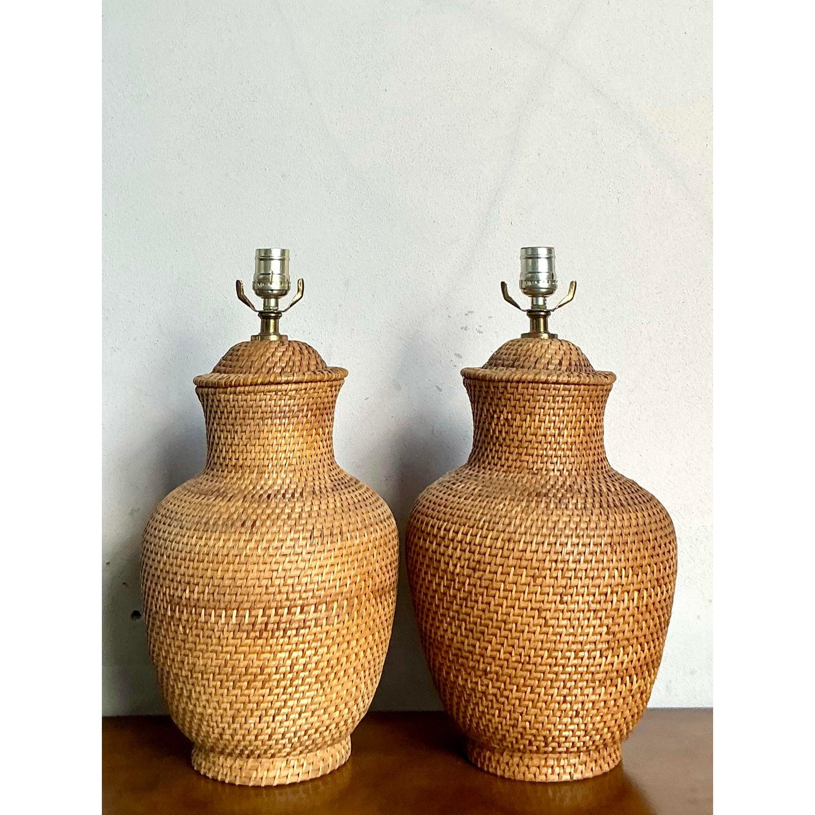 Embrace the warm, organic texture of this exquisite pair of vintage woven rattan lamps. Masterfully crafted, each lamp features a classic urn silhouette, meticulously hand-woven from natural rattan to create a piece that is both earthy and