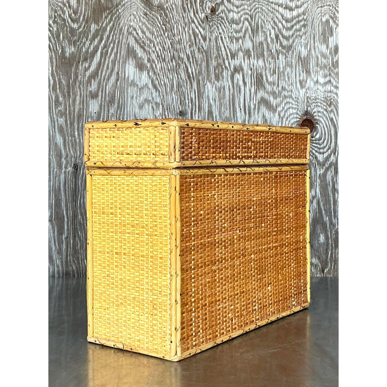 Natürliche Strukturen und zeitloser Charme mit dieser im Boho-Stil geflochtenen Box mit Deckel aus Rattan. Mit seinen komplizierten Flechtmustern und dem stabilen Bambusrahmen strahlt dieses Stück rustikale Eleganz aus und bietet gleichzeitig