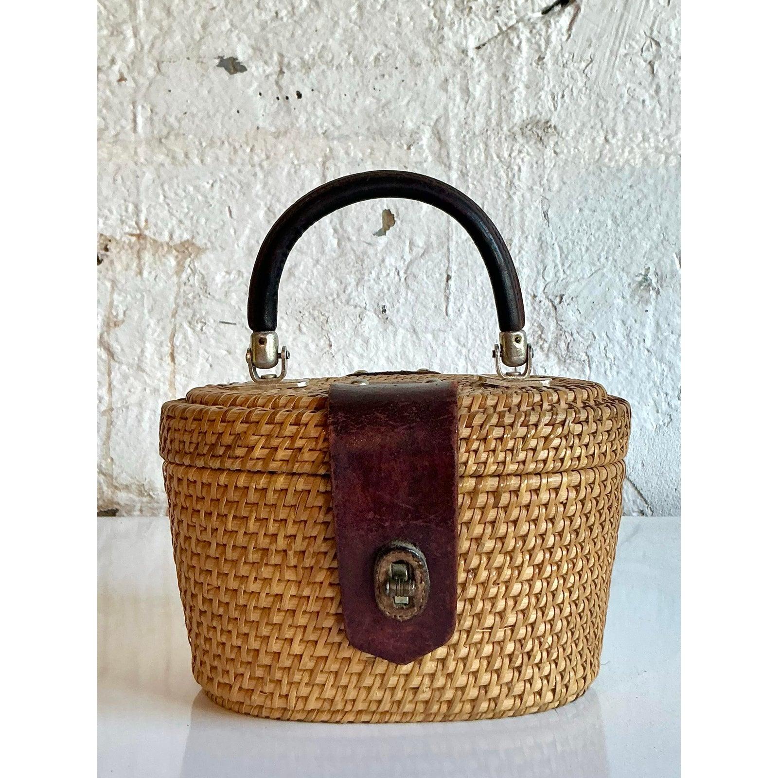 Embrace timeless summer charm with this exquisite vintage woven rattan bag, beautifully crafted in the beloved Nantucket basket style. Its classic oval silhouette features a meticulously hand-woven rattan body, creating a rich, textured surface in