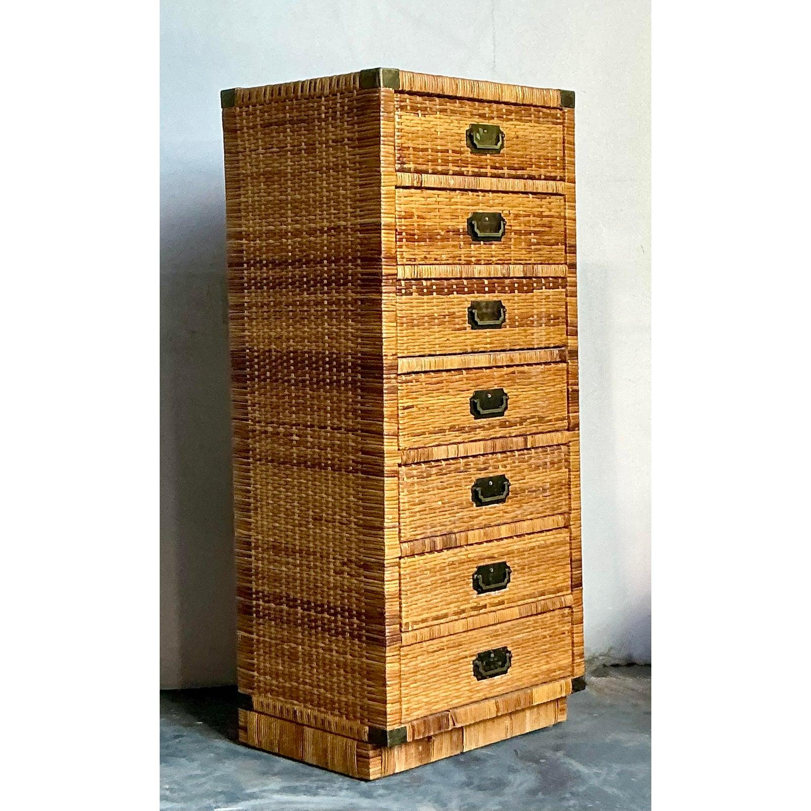 This elegant tall chest of drawers is a superb representation of the Post-1970s tropical and Coastal design movement, seamlessly blending natural texture with refined hardware. The entire structure is meticulously clad in richly woven rattan and