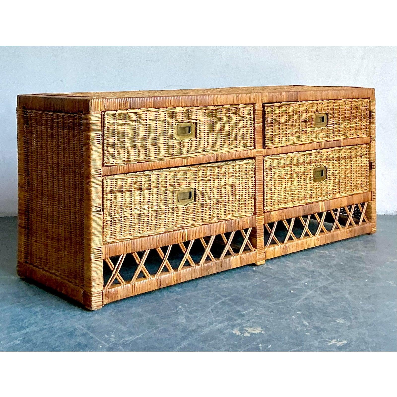 Imbue your living space with the relaxed sophistication of this vintage woven rattan low credenza. Expertly crafted in the 1970s, this piece features a tight, textural wicker weave covering the entire surface, accented by recessed Campaign-style
