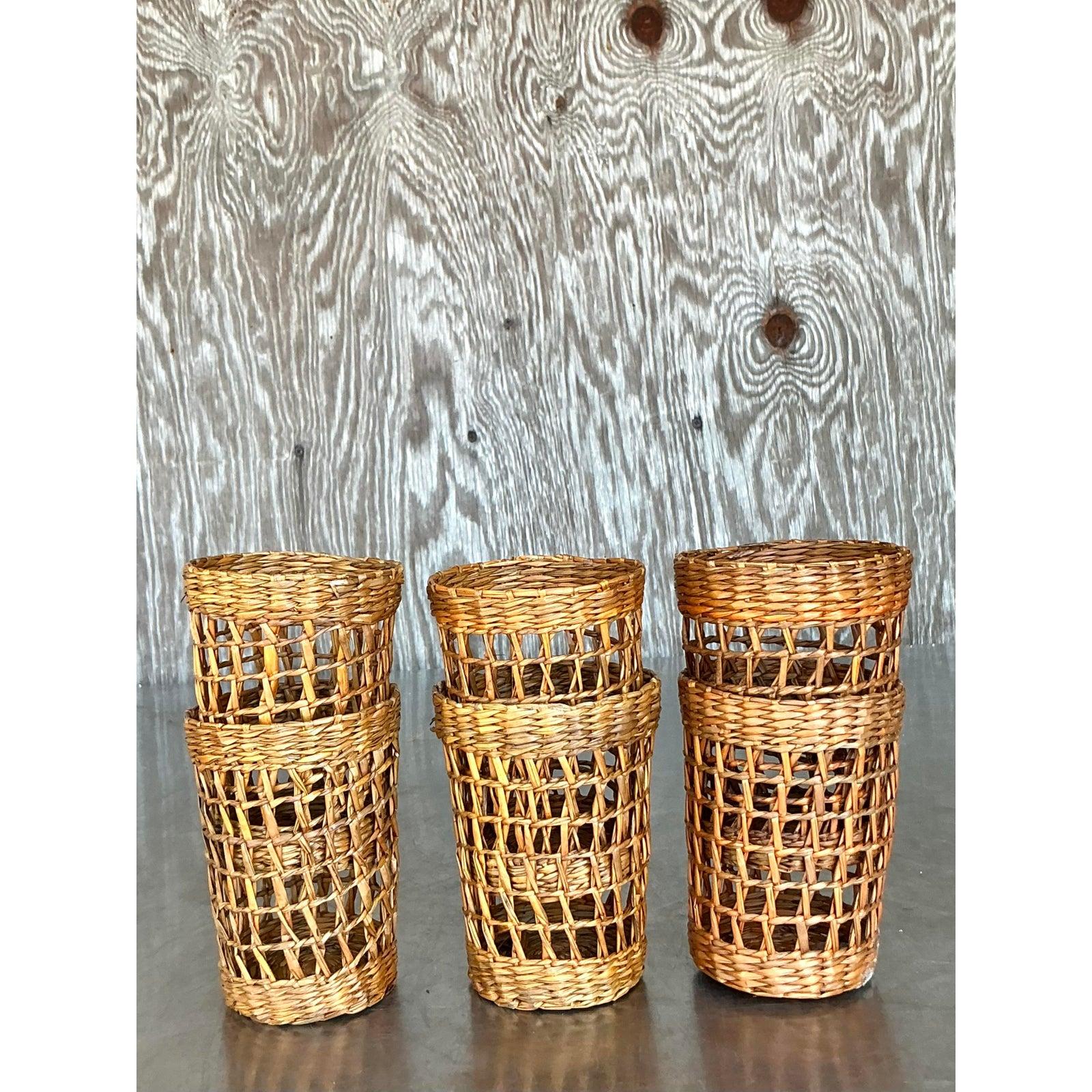 Peppen Sie Ihr Getränkeservice mit diesem charmanten Set aus sechs Becherglashüllen im Vintage-Stil auf, die aus geflochtenem Rattan oder Naturfaser gefertigt sind. Jede Hülle hat eine leicht verjüngte zylindrische Form und ein ansprechendes offenes
