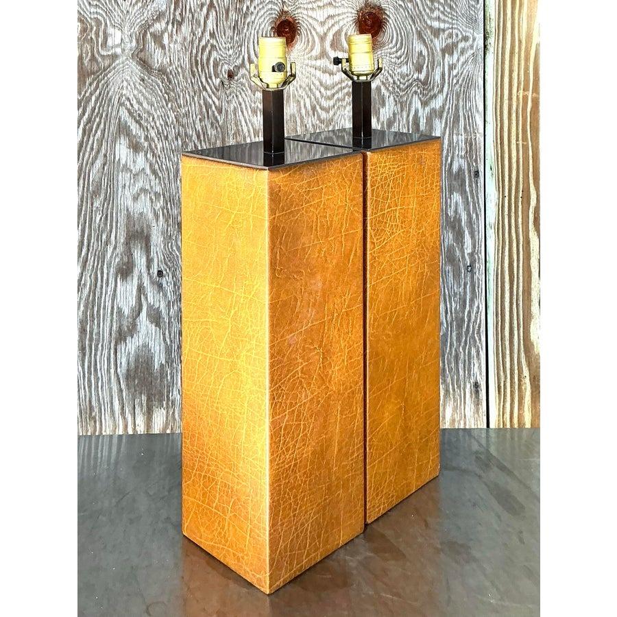 Eleva il tuo spazio con questa squisita coppia di lampade vintage boho in pelle avvolte. L'esclusivo design rettangolare, avvolto in pelle color caramello, emana un fascino rustico e un'eleganza bohémien. Perfettamente adatte a diversi stili di