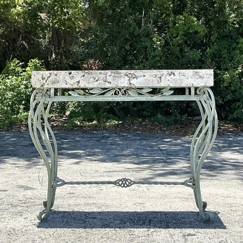 Capture the rustic elegance of a European garden with this exquisite vintage console table. This remarkable piece beautifully marries a raw, organic coquina stone top with a gracefully forged iron base. The thick, fossil-rich slab of coquina tells a