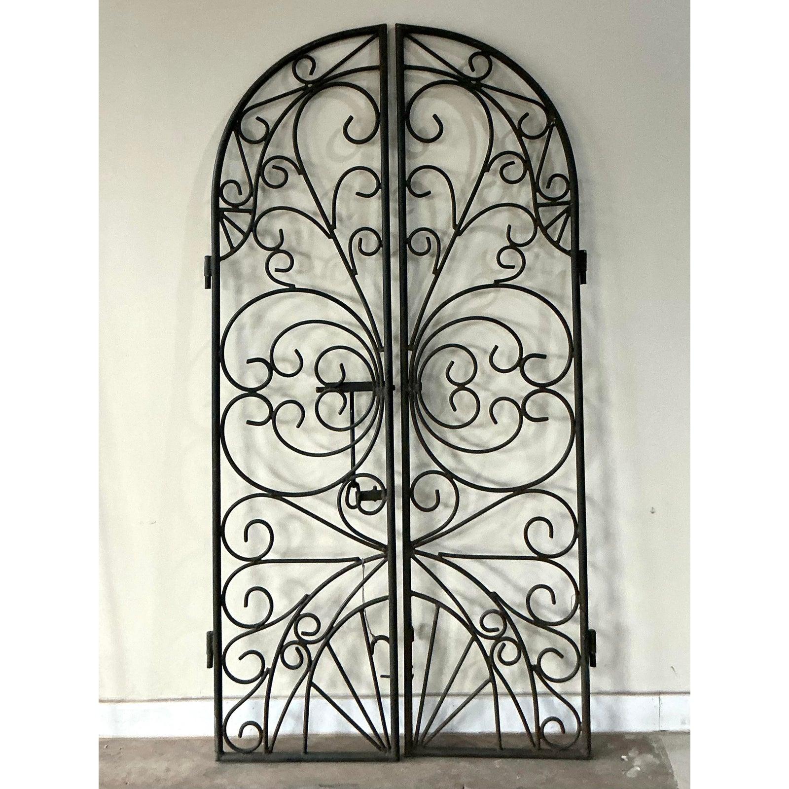 This stunning pair of vintage wrought iron gates offers exceptional architectural elegance, capturing the romantic spirit of Mediterranean design and Spanish Revival aesthetics. The exquisite craftsmanship is evident in the detailed, hand-forged