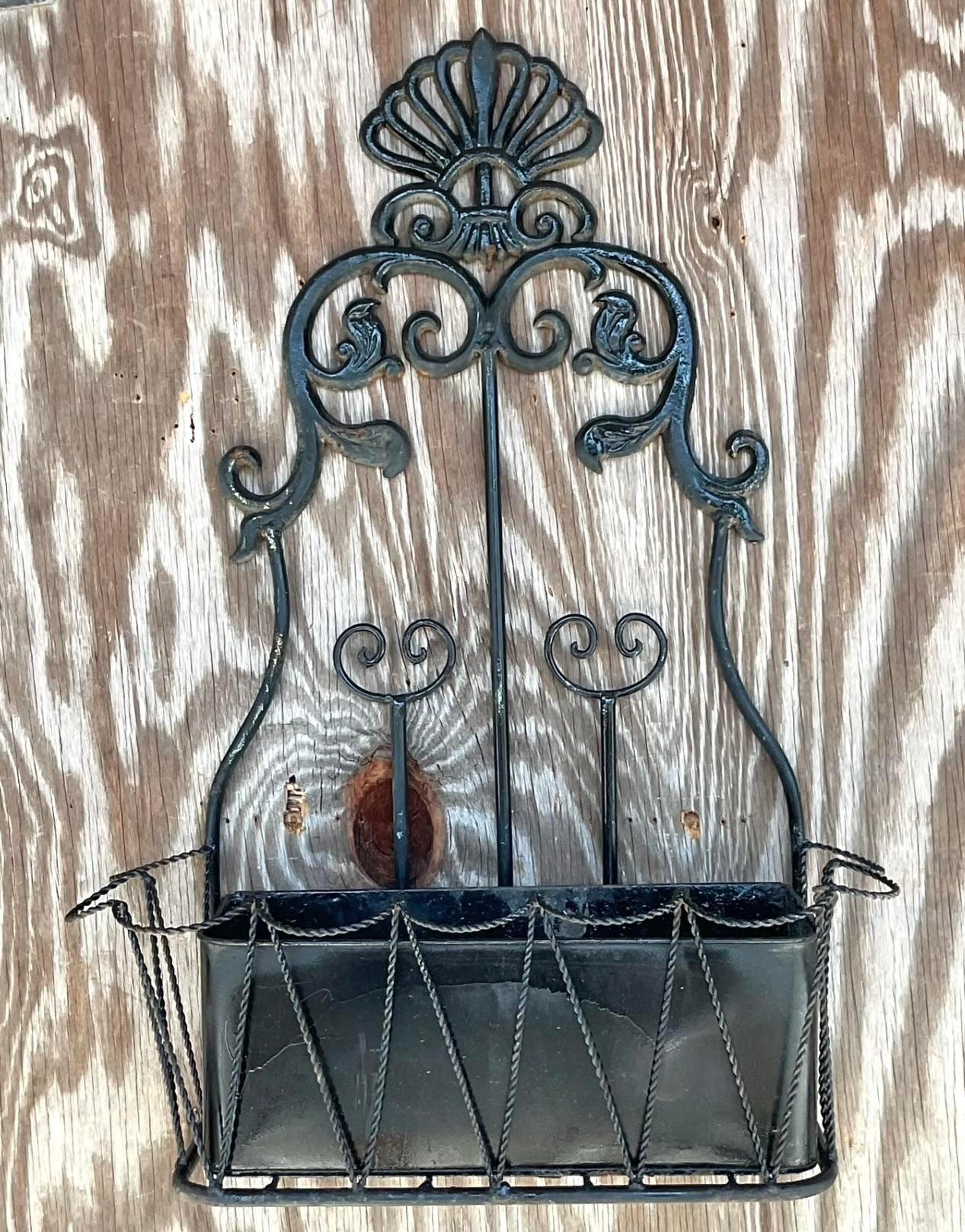 A fantastic vintage Boho wall planter. A chic scroll design in black wrought iron. A generous pocket for your favorite flowers, shells or pine cones. You decide! Perfect indoors or outside in a covered area. Acquired from a Palm Beach estate.