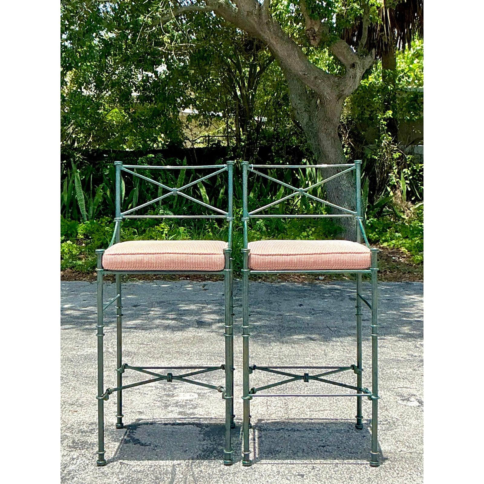 Elevate your entertaining space with this captivating pair of vintage wrought iron bar stools. Their unique design, featuring distinctive knot or faux bamboo detailing and classic X-braces on the back and stretchers, exudes a charming bohemian