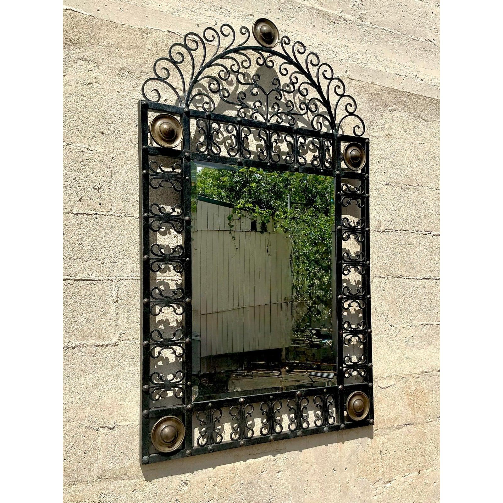 Élevez votre espace avec ce superbe miroir vintage en fer forgé, une pièce d'apparat exquise qui allie un savoir-faire artisanal complexe à un design intemporel. Le cadre en fer forgé à la main présente de délicates volutes, créant un équilibre