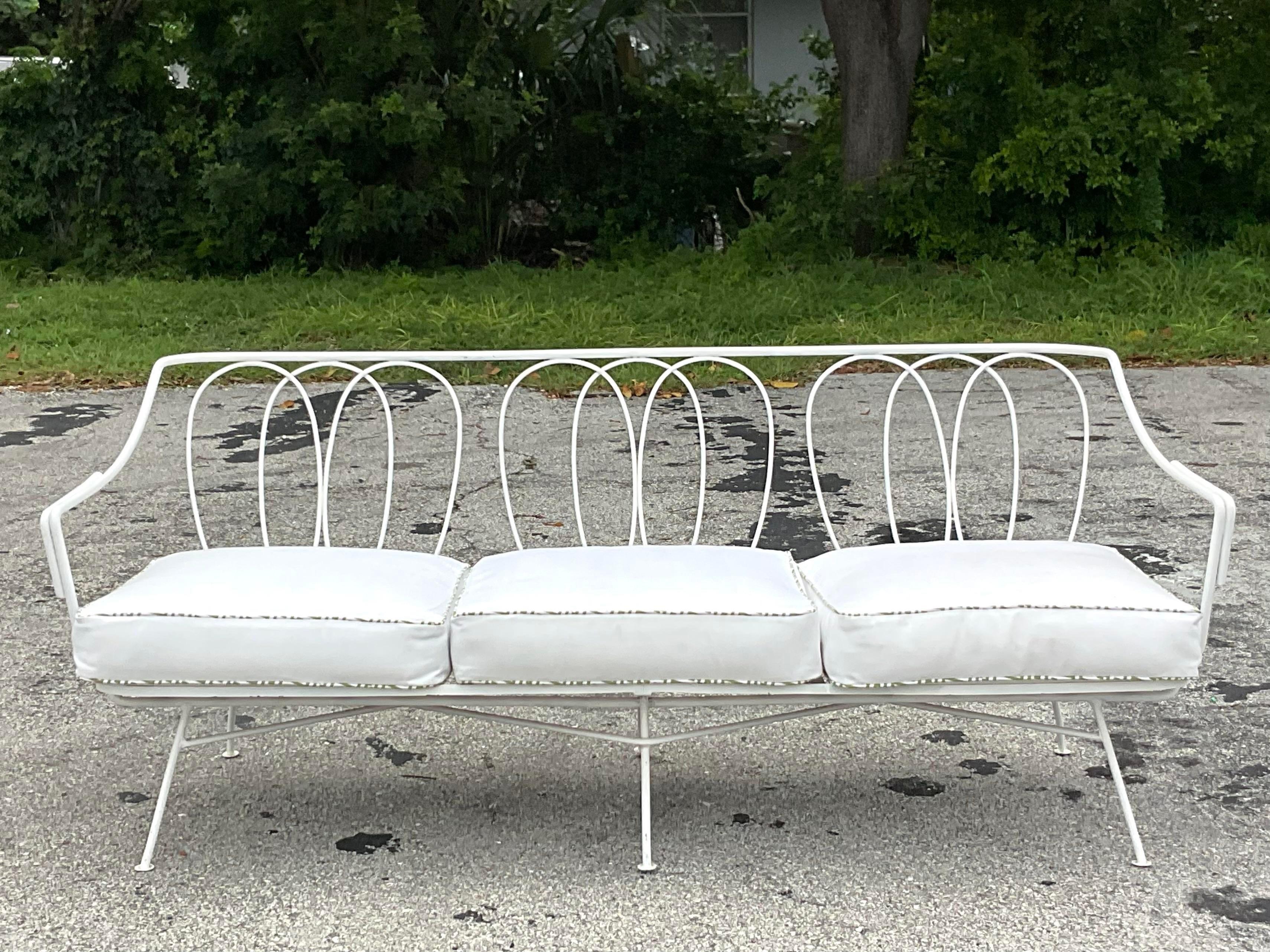A fantastic vintage Outdoor wrought iron sofa. Beautiful loop design with a white painted finish. Done in the manner of Maurizio Tempestini for Salterini. Coordinating cushions with green and white welting. Matching chair also available on my page.