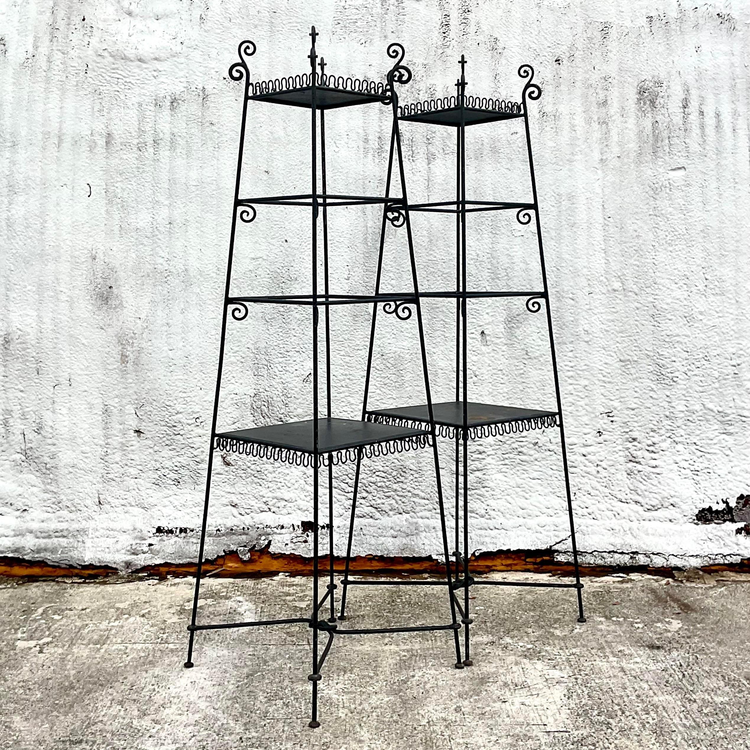 A fabulous pair of vintage Regency etagere. A chic black wrought iron frame with a tapered shape and squiggle detail along the edge. Tall and impressive in size. Acquired from a Palm Beach estate.