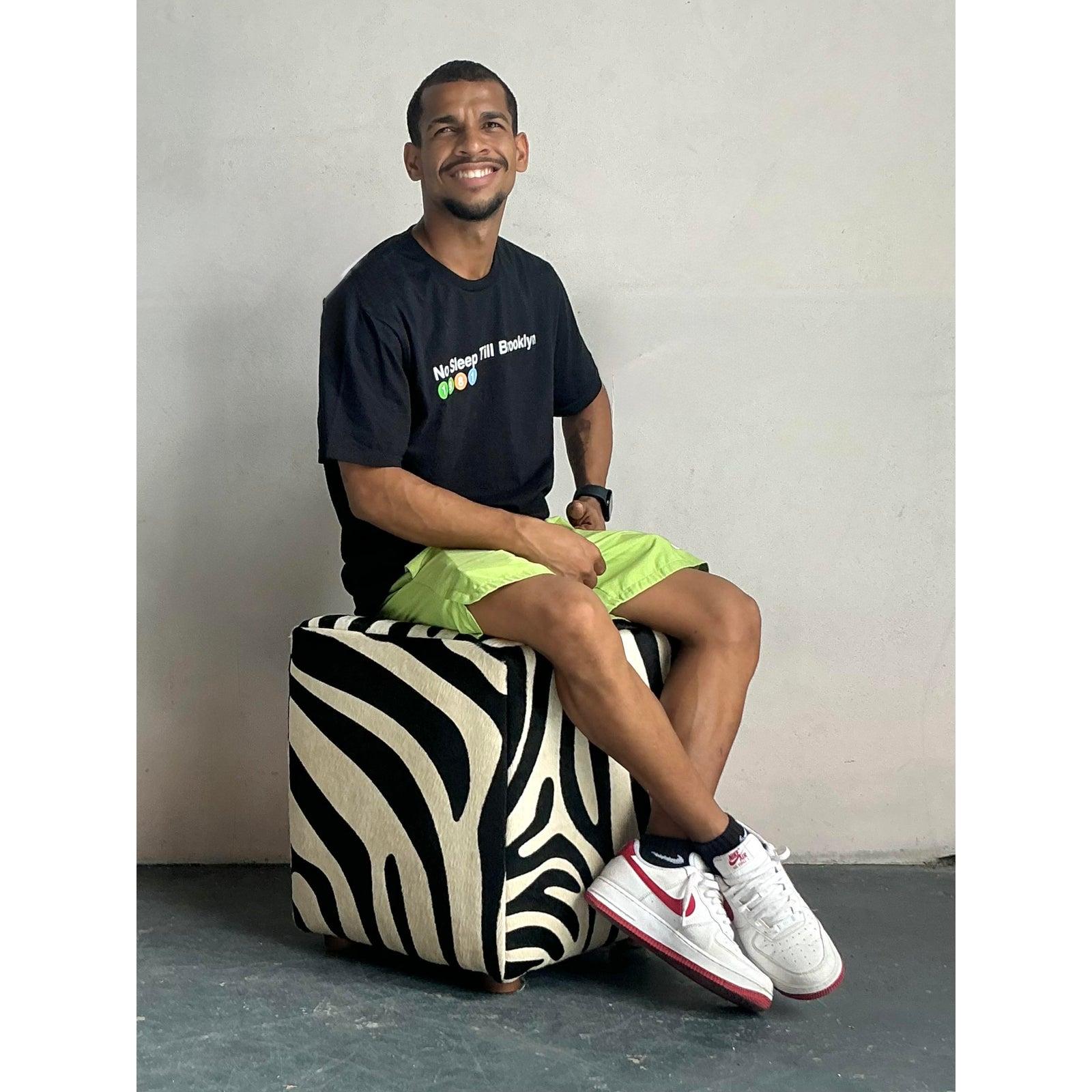 Inject a wild and luxurious touch into your living space with this captivating vintage Boho zebra print ottoman. Upholstered in genuine hair-on-hide, this cube-shaped stool features a striking black and white zebra pattern that immediately commands