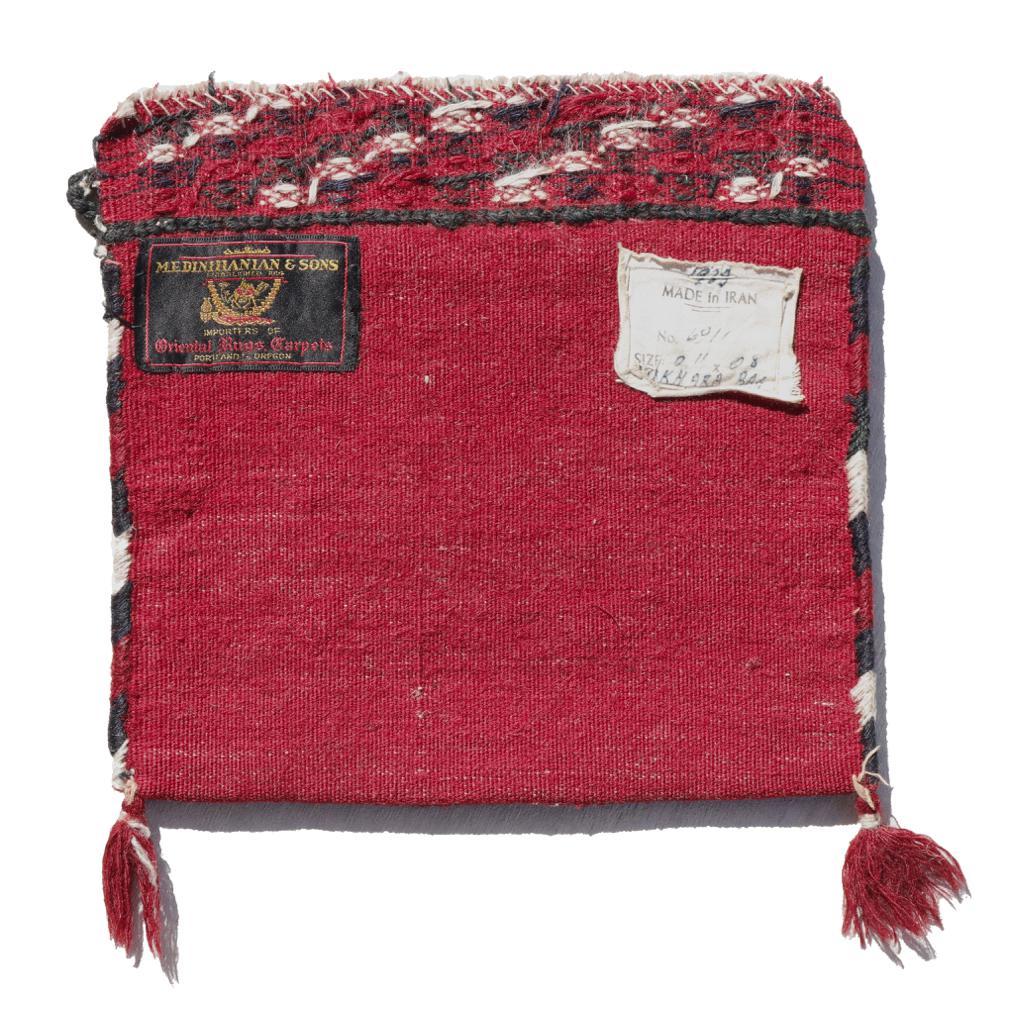 Una borsa Bokhara Saddle vintage, Iran. Un finissimo vello di lana in nodo turco strettamente intrecciato su una base interamente in lana. Un pannello frontale geometrico in bianco e nero su un campo rosso intenso, composto da un medaglione