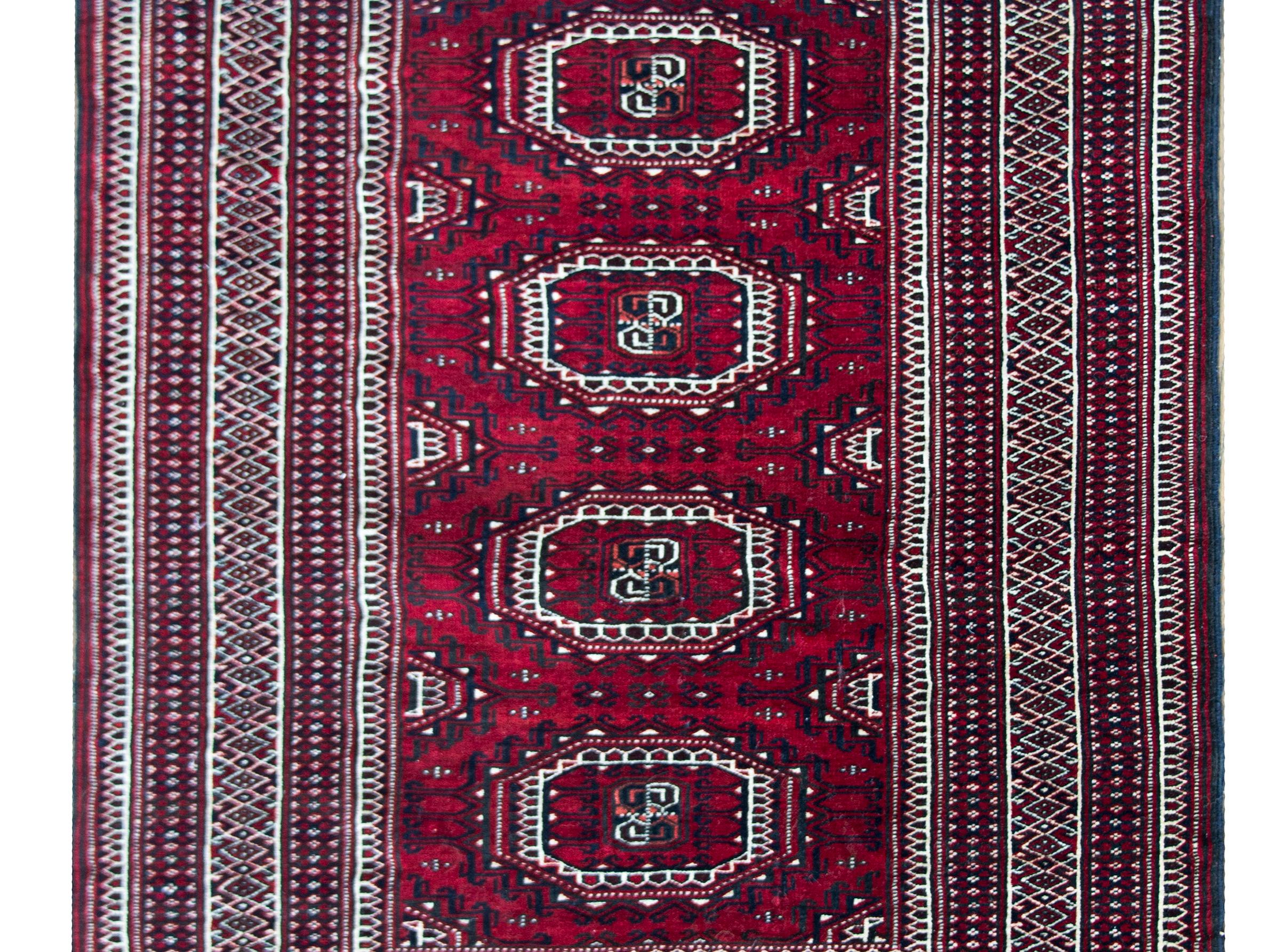 A beautiful late 20th century Persian Bokhara Turkman rug with four large central medallions surrounded by myriad stylized flowers and all surrounded by the most complex border containing dozens of petite floral patterned stripes, and all woven in