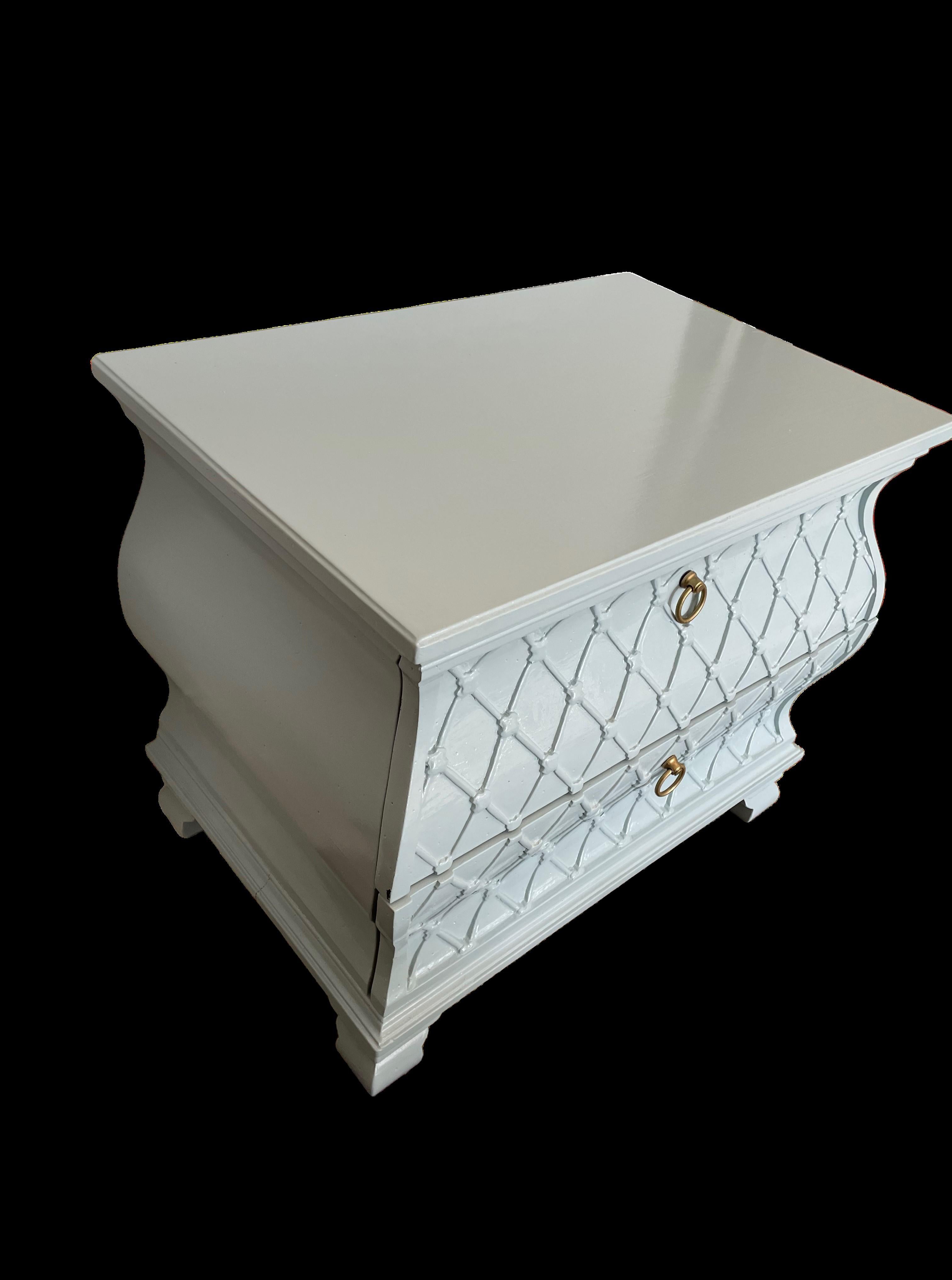 This black lacquered vintage Bombé chest with raised gilded fretwork on its front features curvy French Rococo lines. With two roomy drawers, this piece is simultaneously sumptuous and utilitarian.