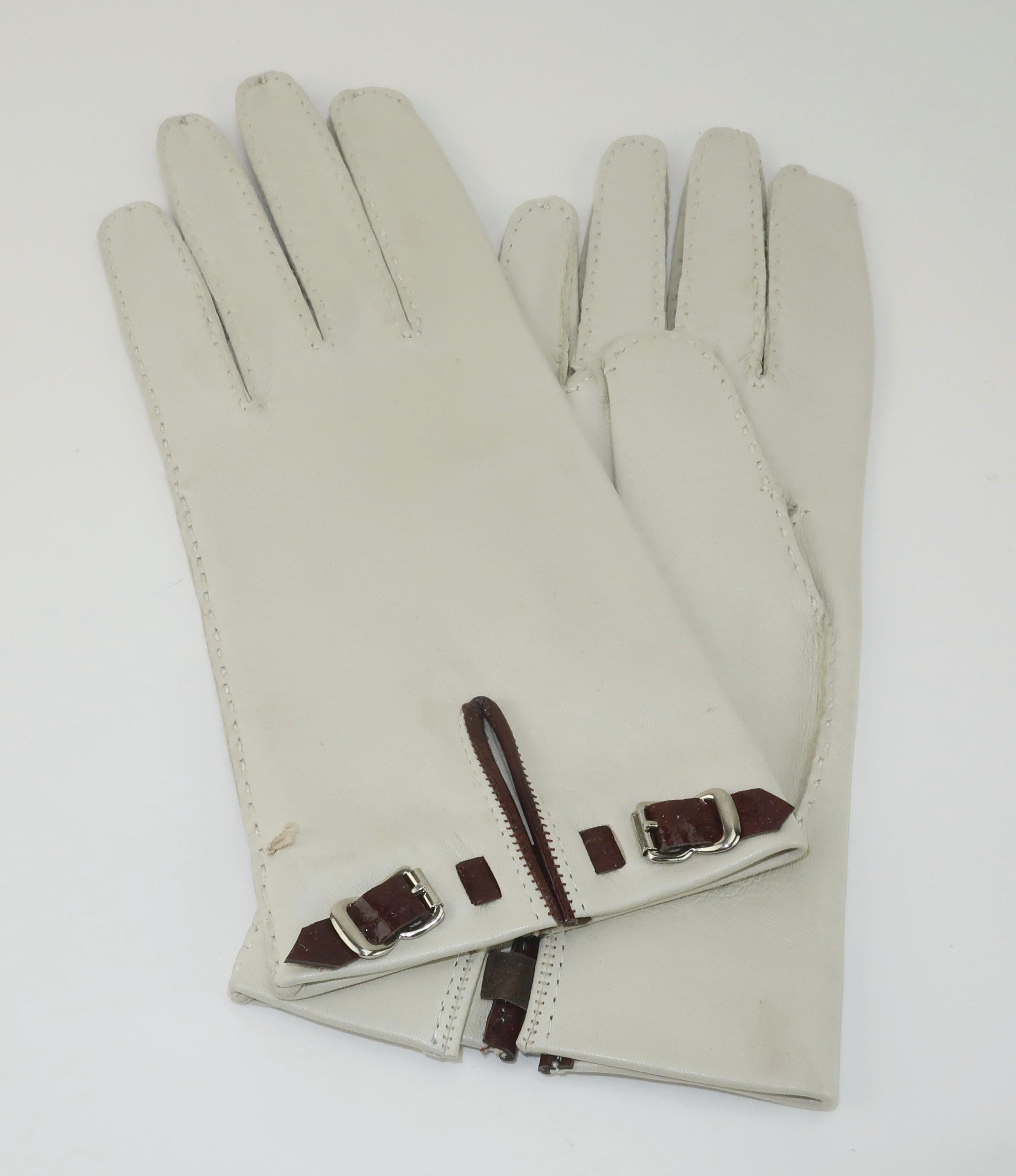 Vintage bone leather gloves with dark burgundy trim and mini faux buckles at the cuffs. The gloves were previously owned though never worn. Marked a size 6 1/2 with no designer label. Beautiful supple leather ... like butter!

Marked 6 1/2 and fits